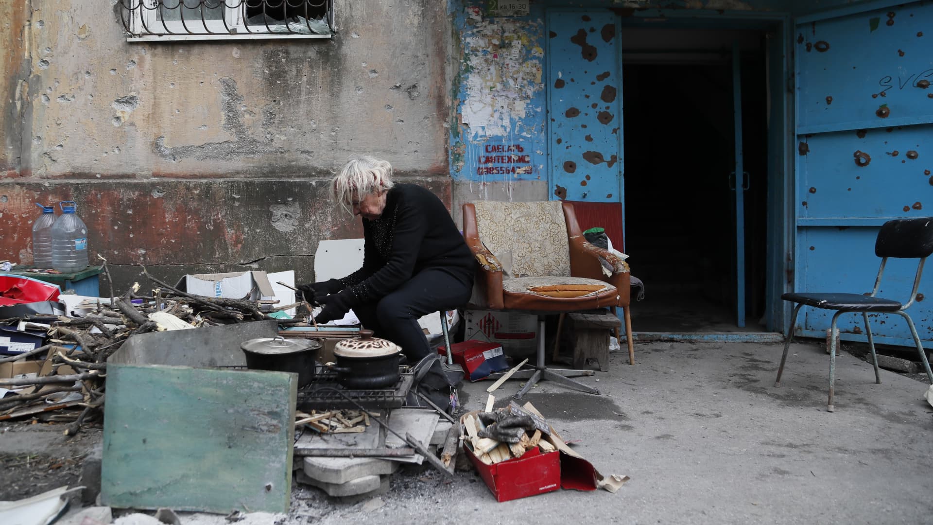 A local resident prepares meal outside a damaged building in the port city of Mariupol, May 15, 2022.