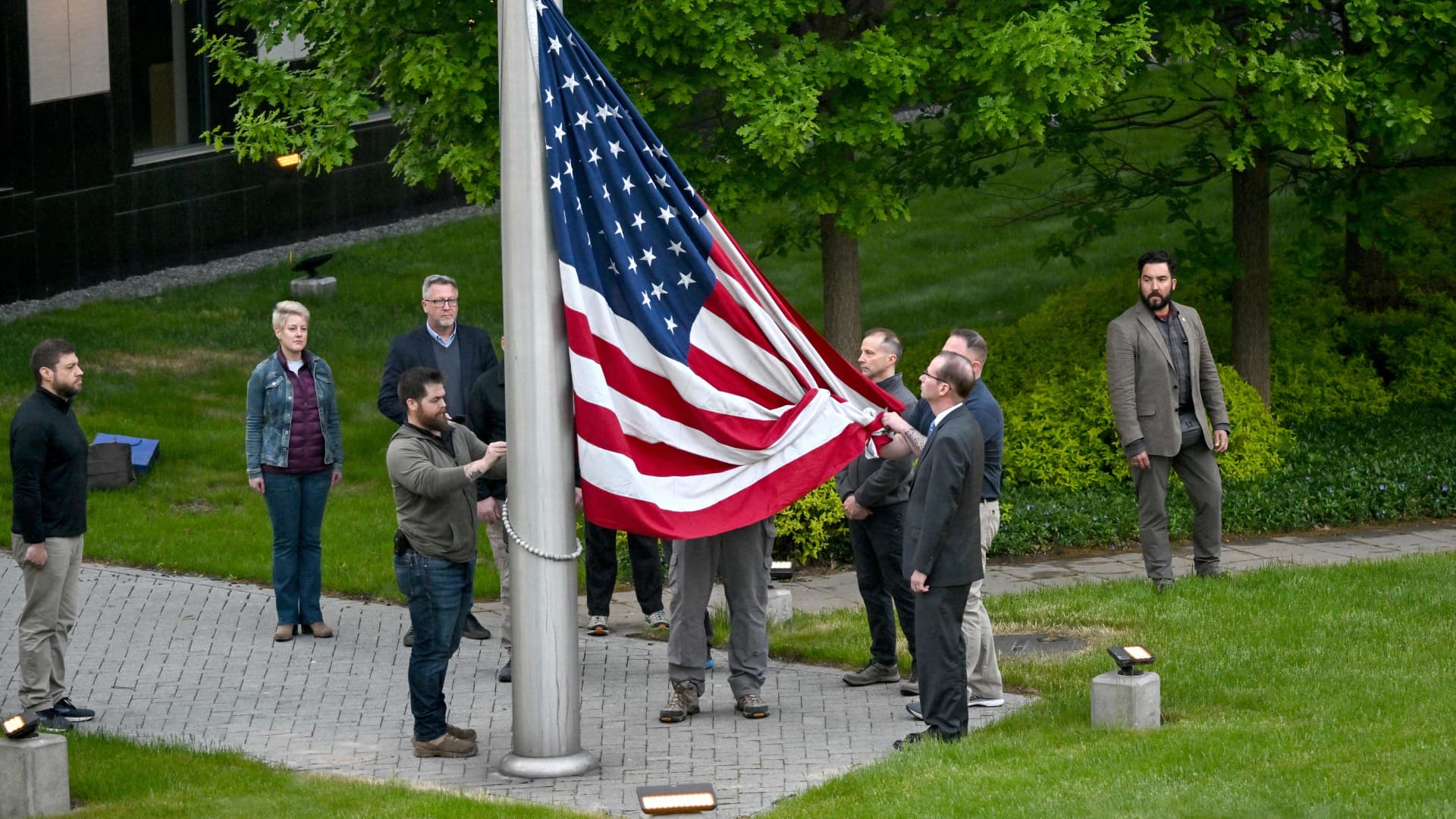 Employees rise up the flag outside the US embassy in Kyiv on May 18, 2022, as the embassy reopens after closing it for three months due to the Russian invasion.