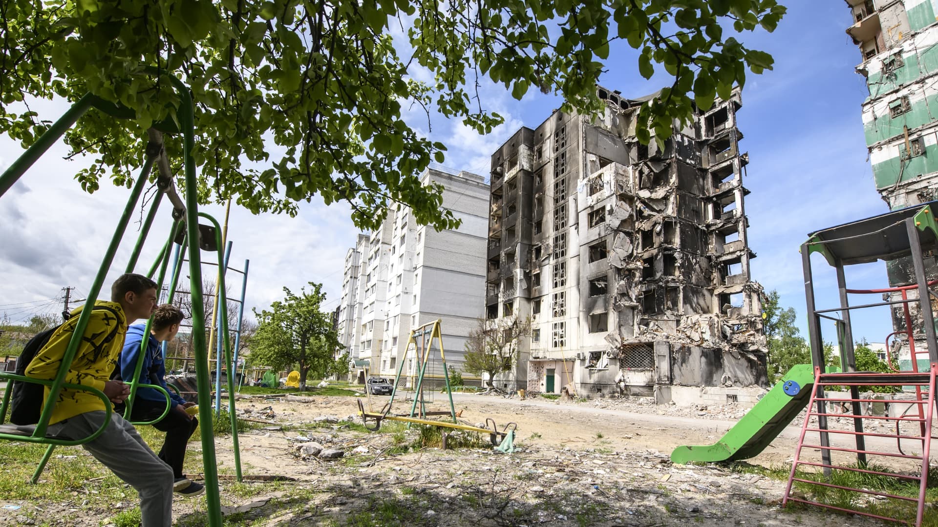Local boys sit on a swing in the yard of an apartment building destroyed by the Russian army airstrike in Ukraine May 13, 2022. The war in Ukraine is expected to continue through the summer and possibly beyond, presidential advisor Oleksii Arestovych said, cited by NBC News.