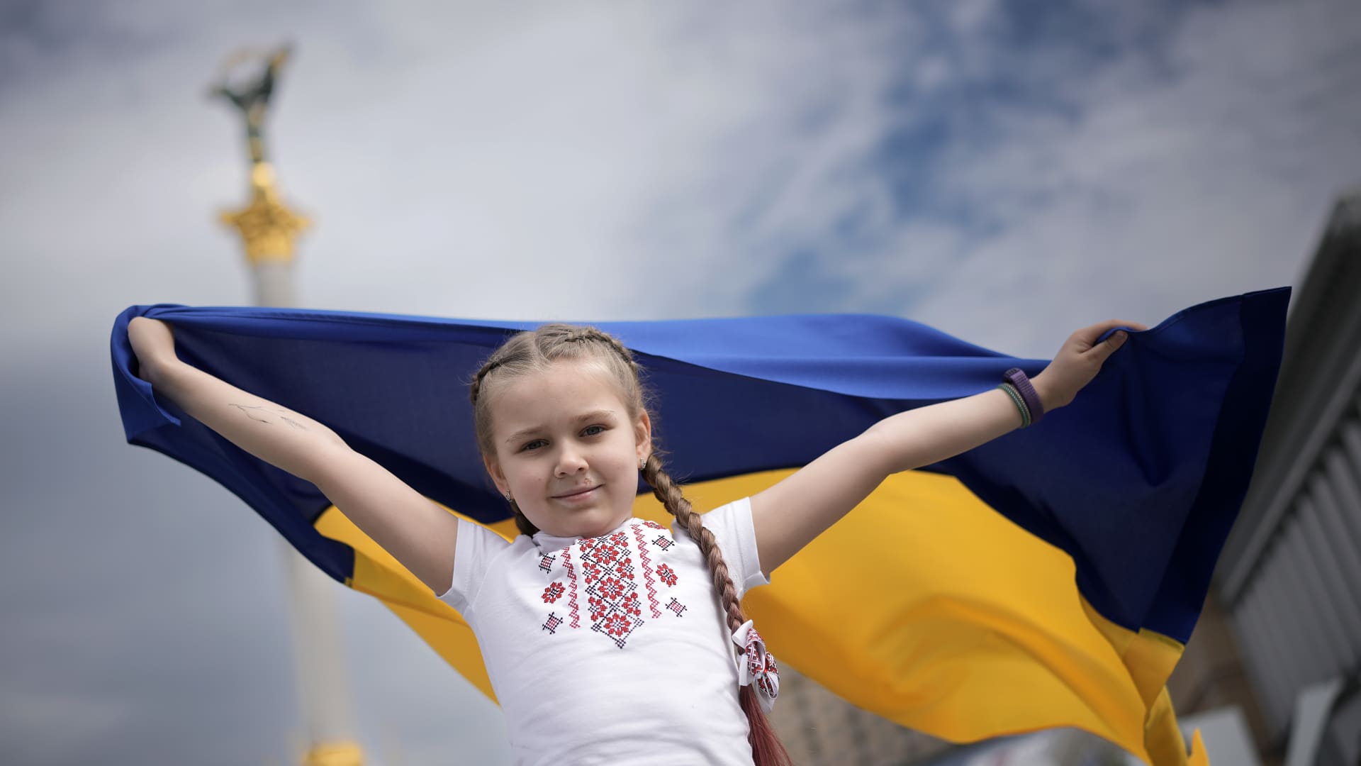 A young girl waves a Ukrainian flag and poses for her mothers camera as she celebrates World Vyshyvanka Day in central Kyiv on May 19, 2022 in Kyiv, Ukraine.