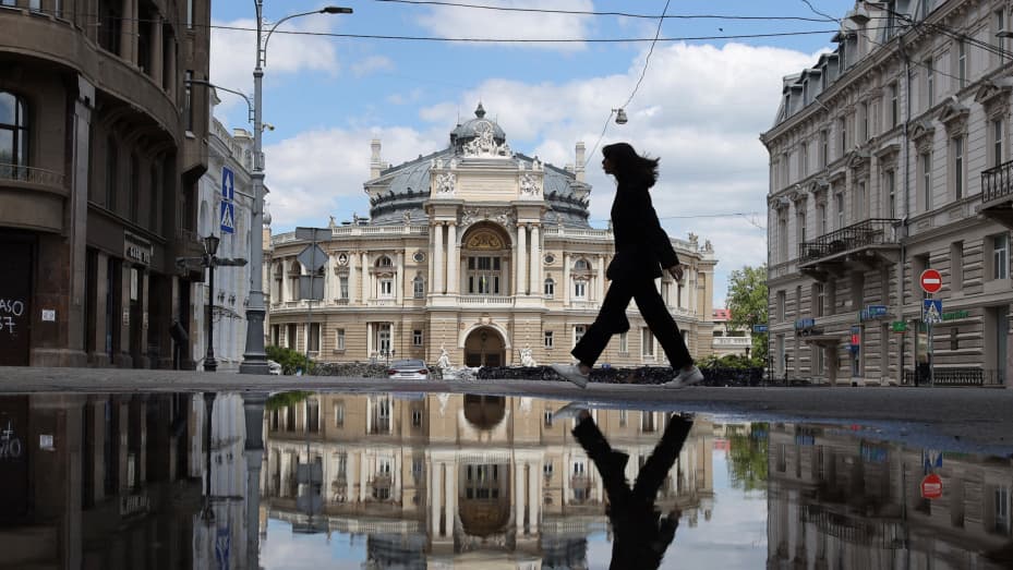 A girl reflects in a puddle as she walks in the Black Sea Ukrainian city of Odessa on May 19, 2022.