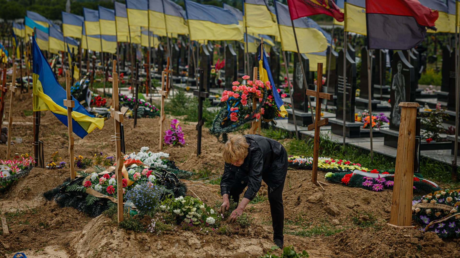A woman plants flowers at the grave of Stanislav Hvostov, 22, a Ukrainian serviceman killed during the Russian invasion of Ukraine in the military section of the Kharkiv cemetery number 18 in in Bezlioudivka, eastern Ukraine.