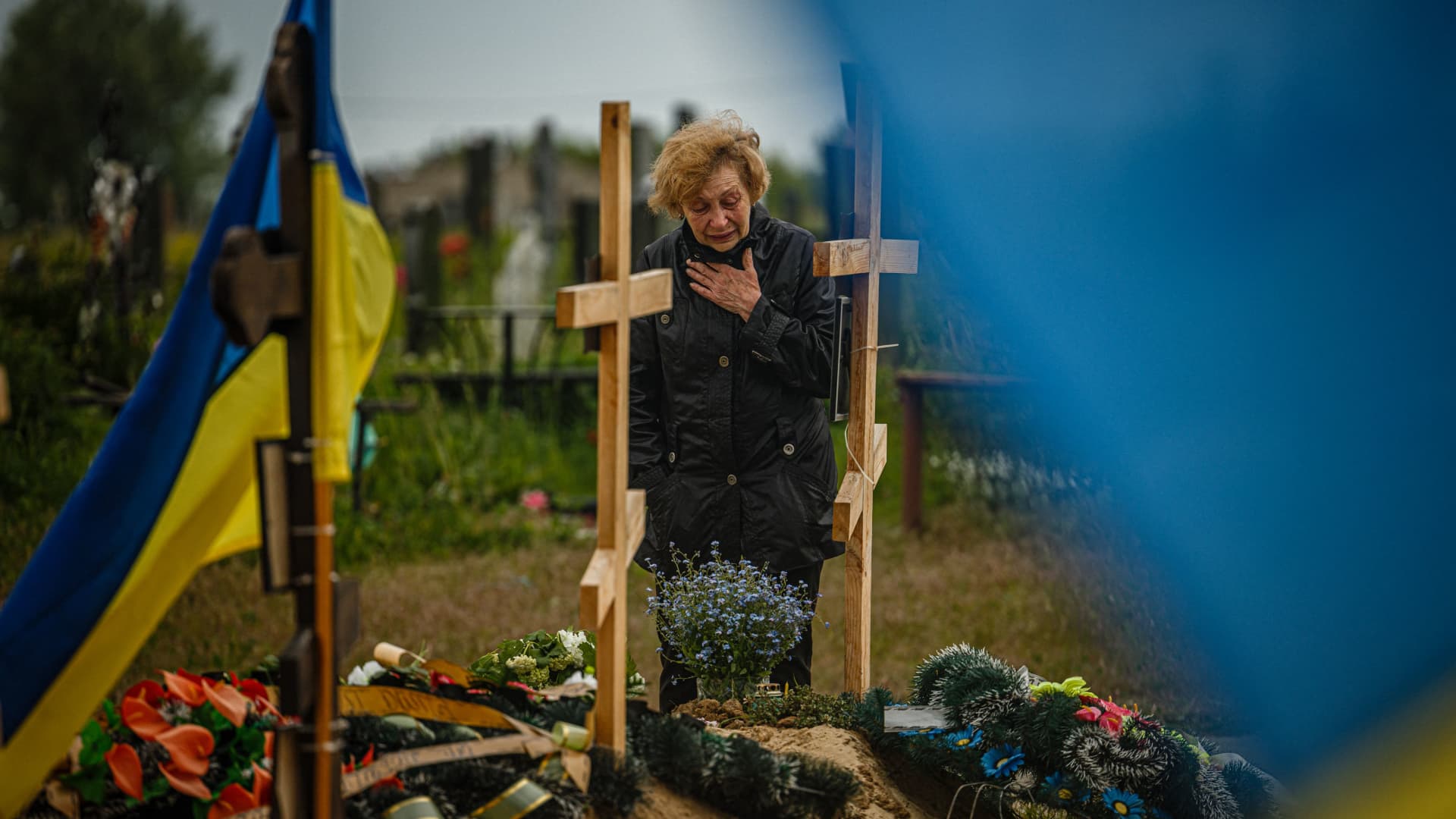 A woman mourns while visiting the grave of Stanislav Hvostov, 22, a Ukrainian serviceman killed during the Russian invasion of Ukraine, in the military section of the Kharkiv cemetery number 18 in Bezlioudivka, eastern Ukraine on May 21, 2022.