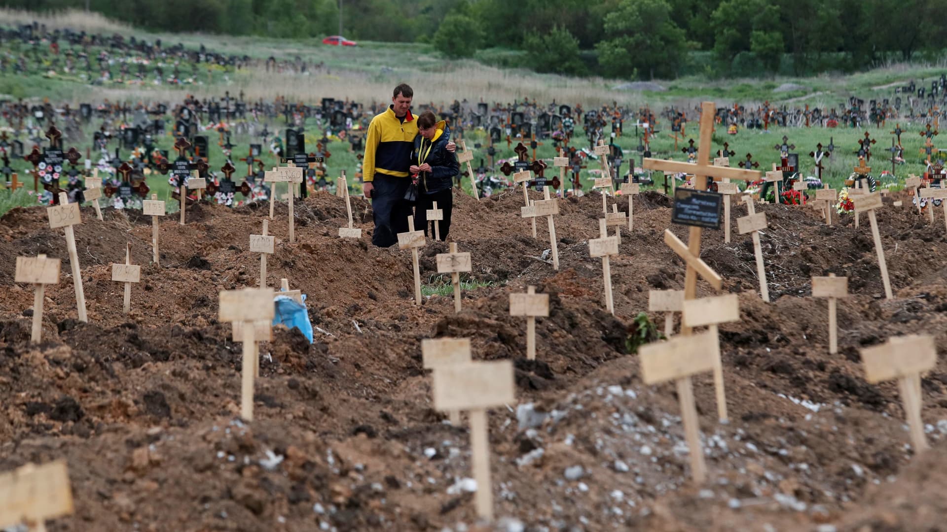 People stand amid newly-made graves at a cemetery in the course of Ukraine-Russia conflict in the settlement of Staryi Krym outside Mariupol, Ukraine May 22, 2022. 