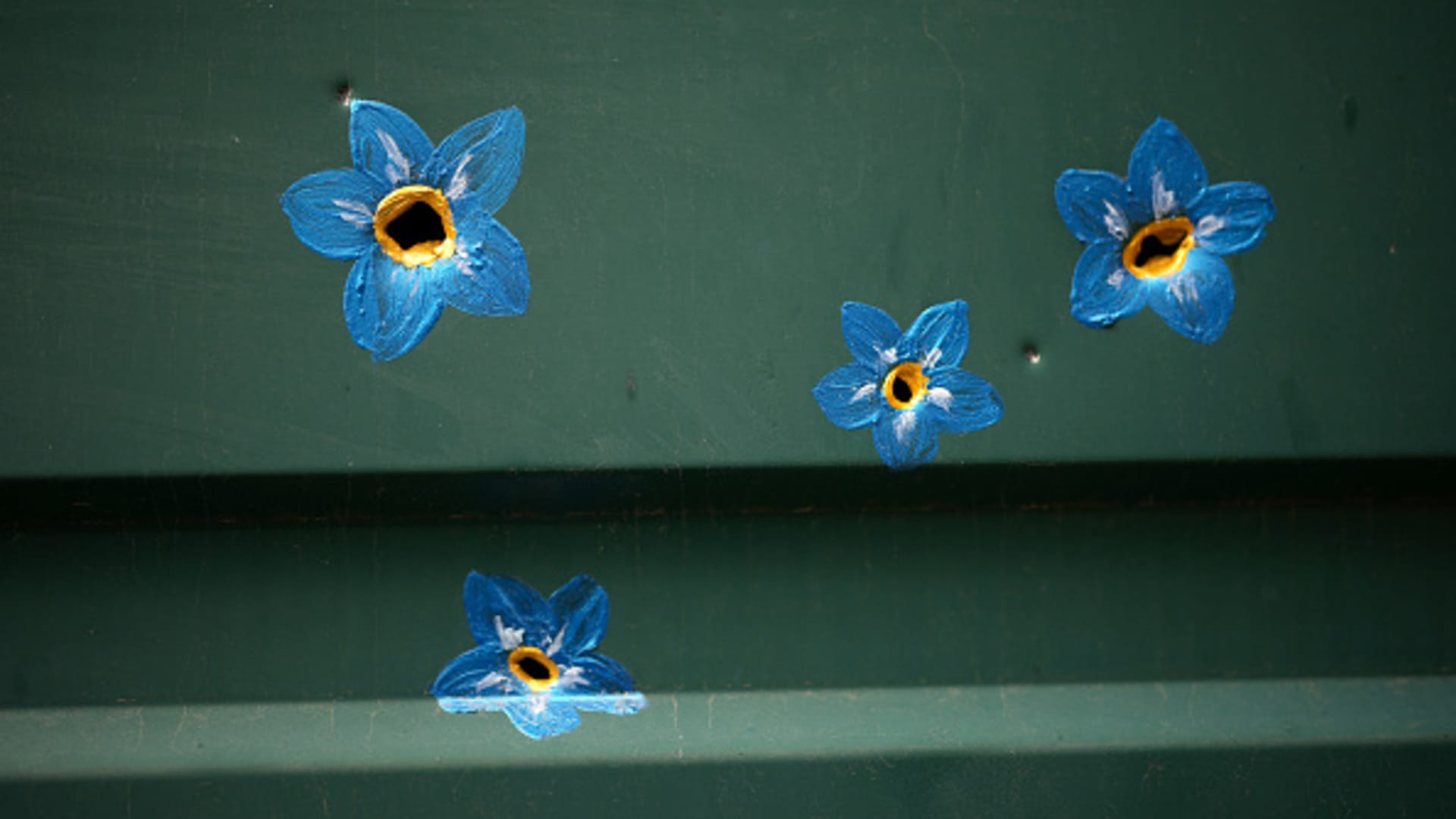 Forget-me-not flowers painted around bullet and shrapnel holes by Canadian artist Ivanka Siolkowsky in the war torn suburb of Bucha on May 23, 2022 in Bucha, Ukraine