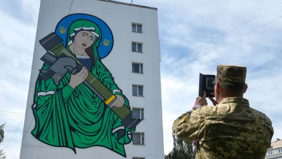 Ukrainian soldiers take pictures of a mural titled 'Saint Javelin' dedicated to the British portable surface-to-air missile has been unveiled on the side of a Kyiv apartment block on May 25, 2022 in Kyiv, Ukraine. The artwork by illustrator and artist Chris Shaw is in reference to the Javelin missile donated to Ukrainian troops to battle against the Russian invasion. Following Russia's retreat from areas around the Ukrainian capital, signs of normal life have returned to Kyiv, with r
