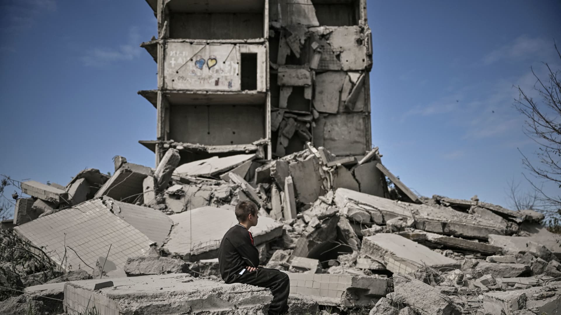 A young boy sits in front of a damaged building after a strike in Kramatorsk in the eastern Ukranian region of Donbas, on May 25, 2022.