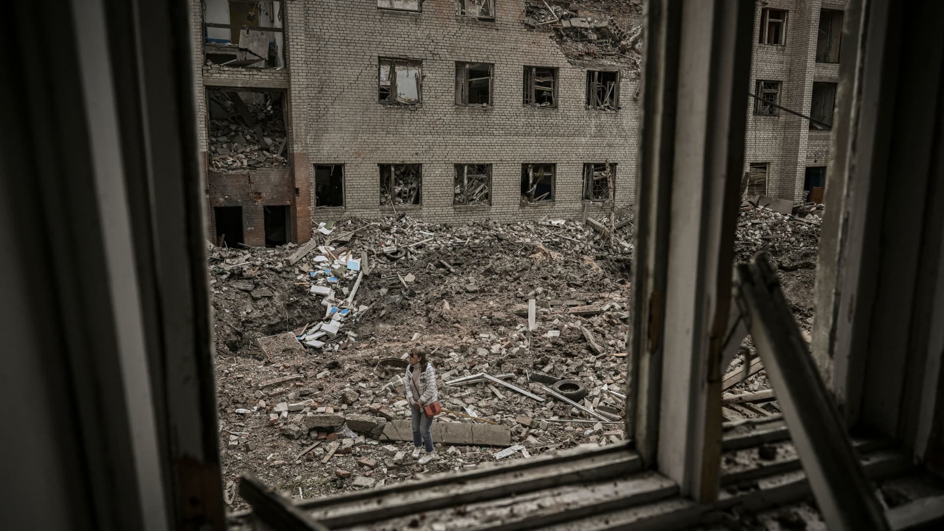 A woman stands in front of a destroyed administration building in the city of Bakhmut in the eastern Ukranian region of Donbas, on May 25, 2022.