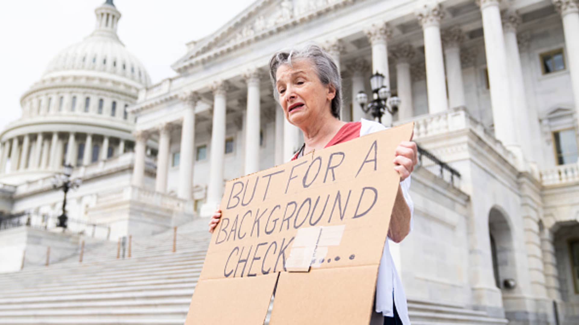 Marnie Beale of Arlington, Va., holds a sign at the Senate steps of the U.S. Capitol calling for background checks on gun purchases on Wednesday, May 25, 2022, after the latest mass shooting at a Texas elementary school.