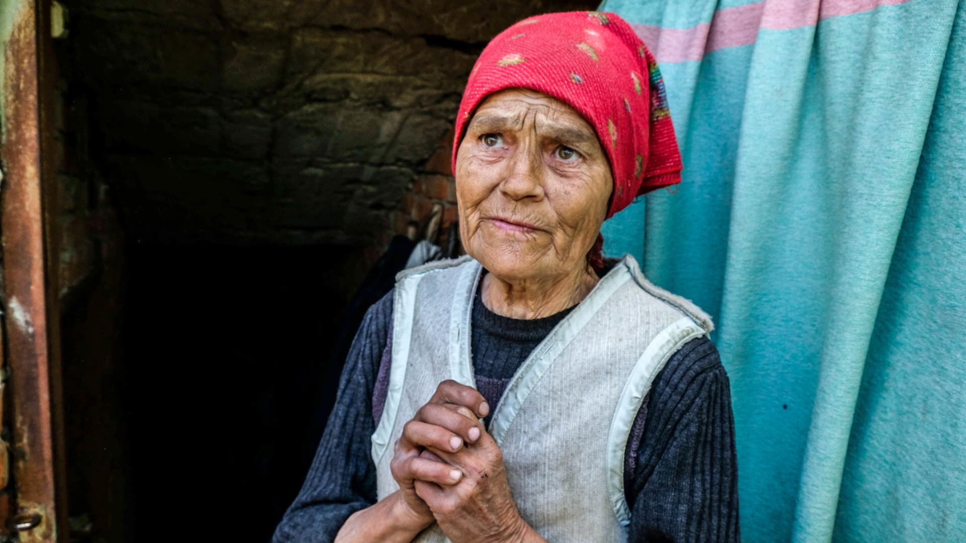 An elderly woman, Alina, 76 years old, in front of the shelter where she sleeps. Siversk is a town of 11,000 inhabitants known for its brick factory. the town is located in the Donetsk region.