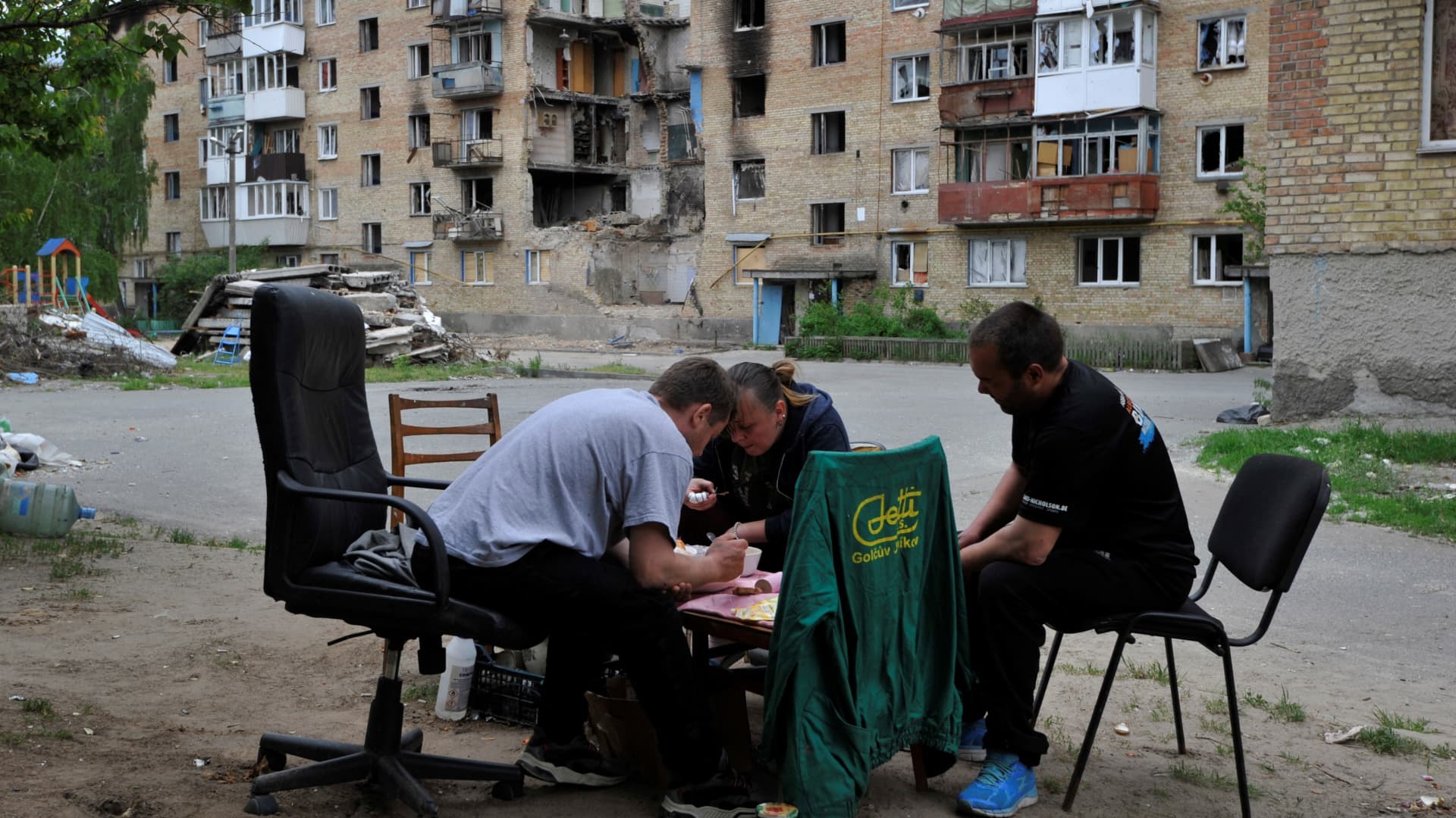 Residents have dinner at the bottom of their building, which has been damaged by shelling in the small town of Moshchun, not far from Kyiv.