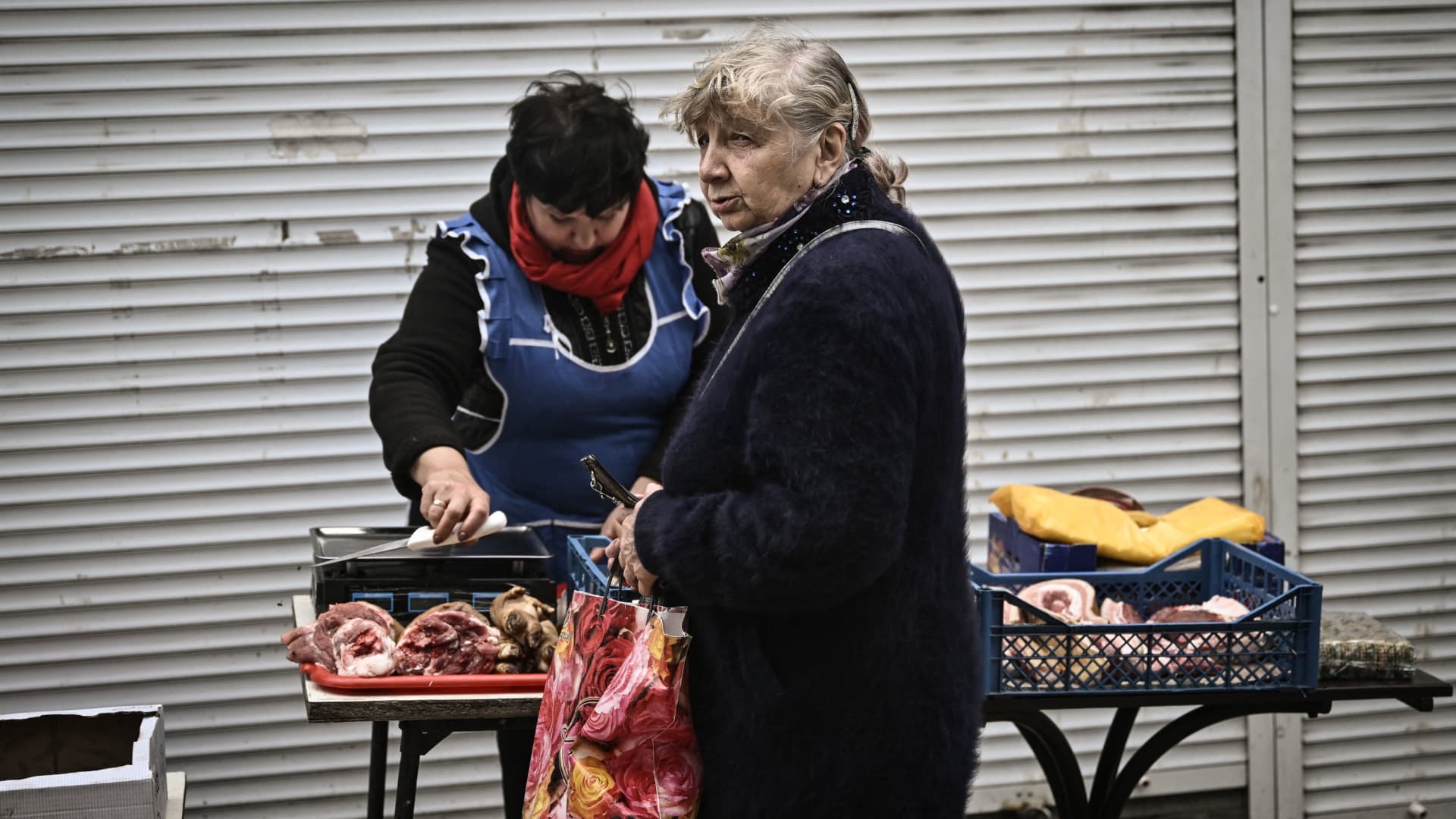 A woman buys meat from a street vendor in the city of Soledar, in the eastern Ukrainian region of Donbas on May 28, 2022.