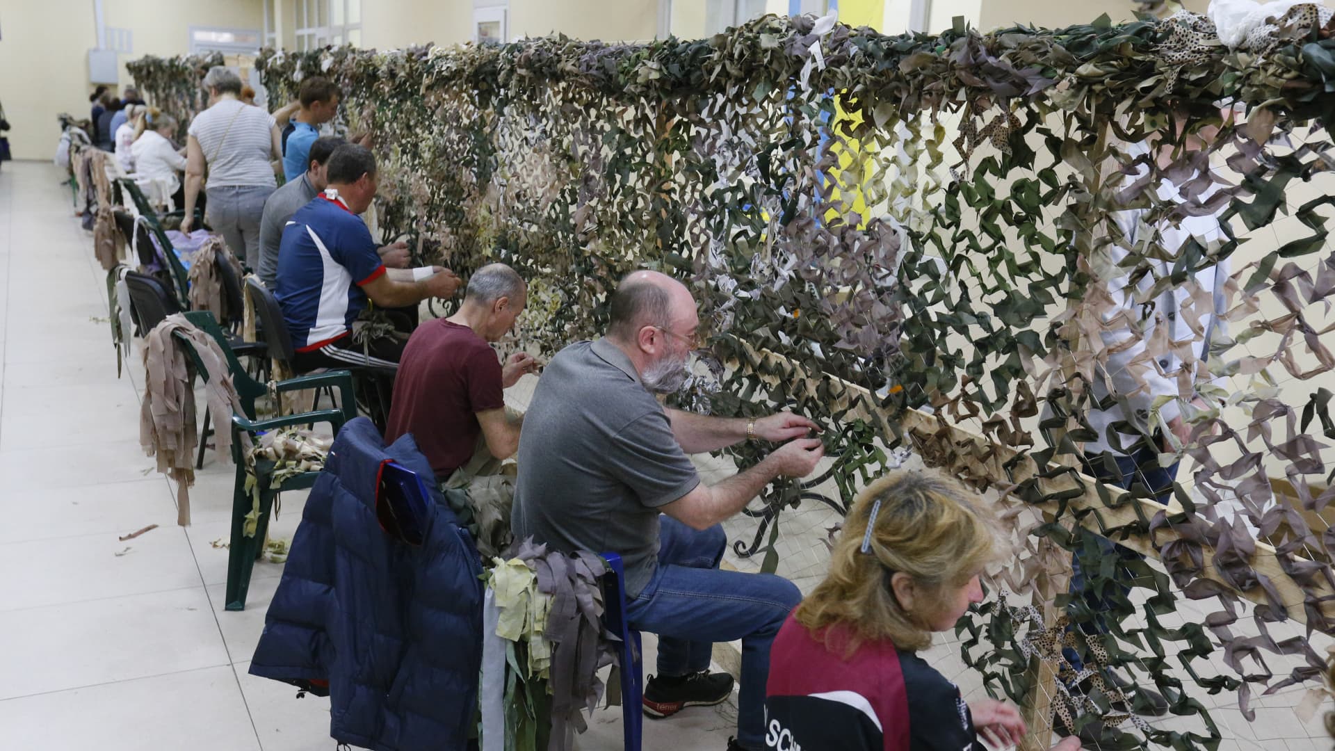 People weave camouflage nets in a weaving camouflage nets center in Odessa, Ukraine, on May 30, 2022. Ukrainian volunteers mark the 500th net which they made for the Ukrainian army. 