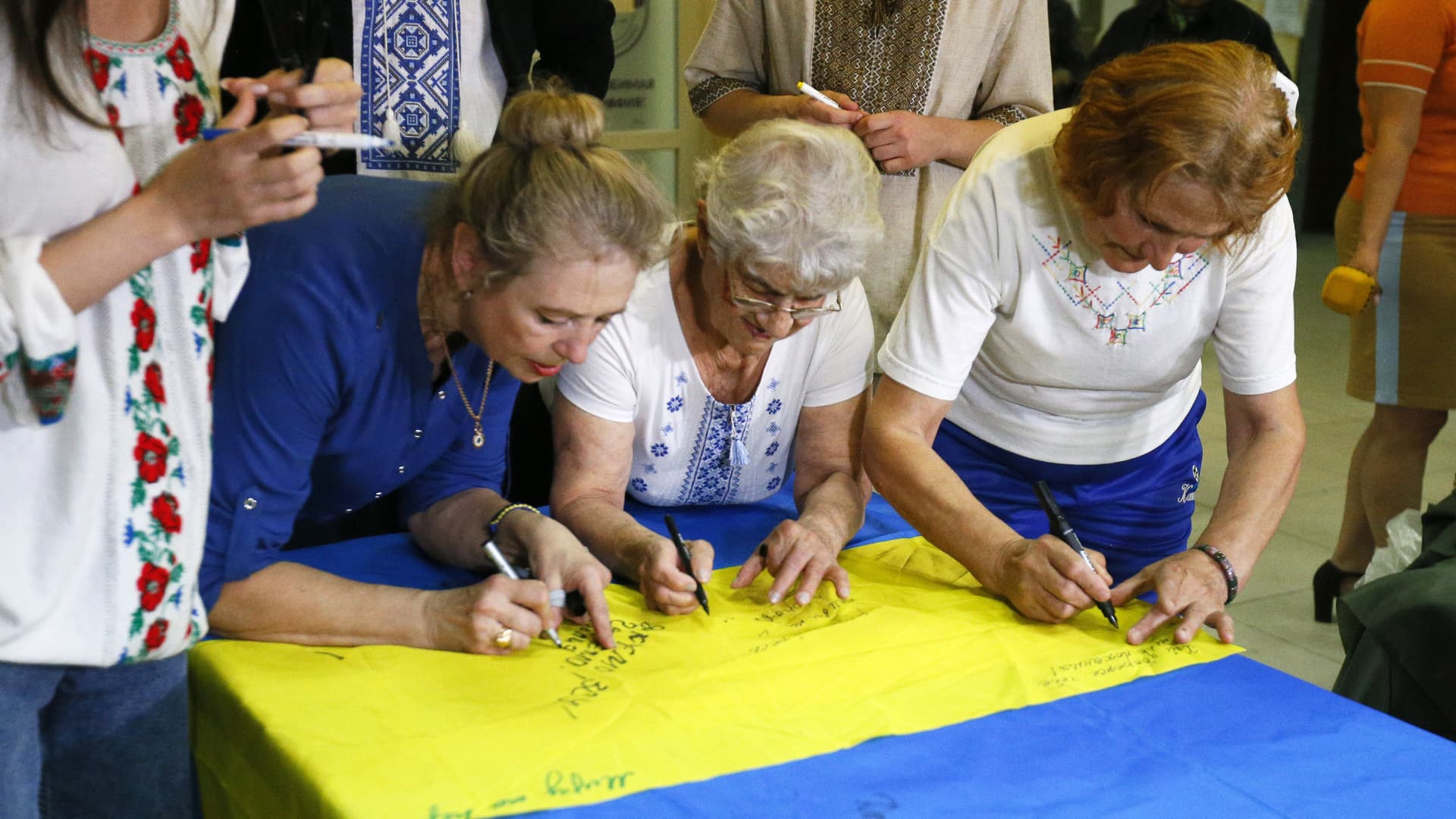 Ukrainian volunteers leave their signatures on the Ukrainian flag which will be handed over to the soldiers of the Ukrainian army, in the weaving camouflage nets center in Odessa, Ukraine, on May 30, 2022. 