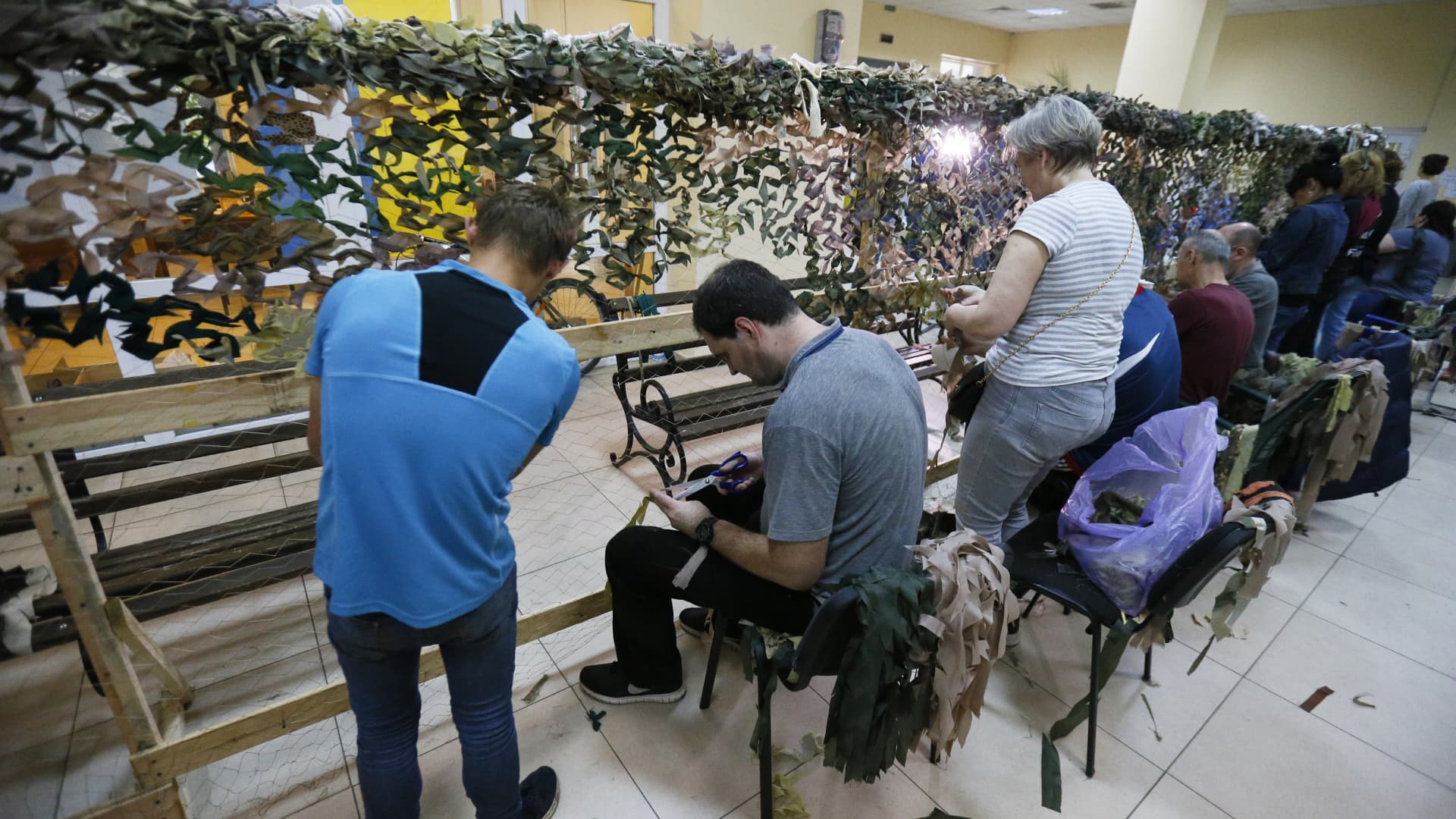 People weave camouflage nets in a weaving camouflage nets center in Odessa, Ukraine, on May 30, 2022. Ukrainian volunteers mark the 500th net which they made for the Ukrainian army.