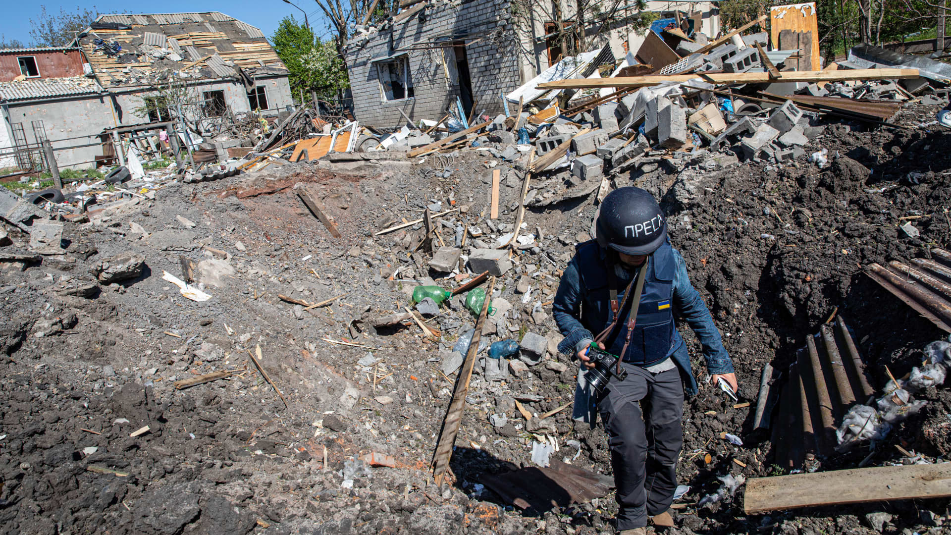 A journalist climbs out of a crater caused by a Russian missile strike in Ukraine. Ukrainian President Volodymyr Zelenskyy says 32 media representatives have been killed since Russia invaded Ukraine on Feb. 24.