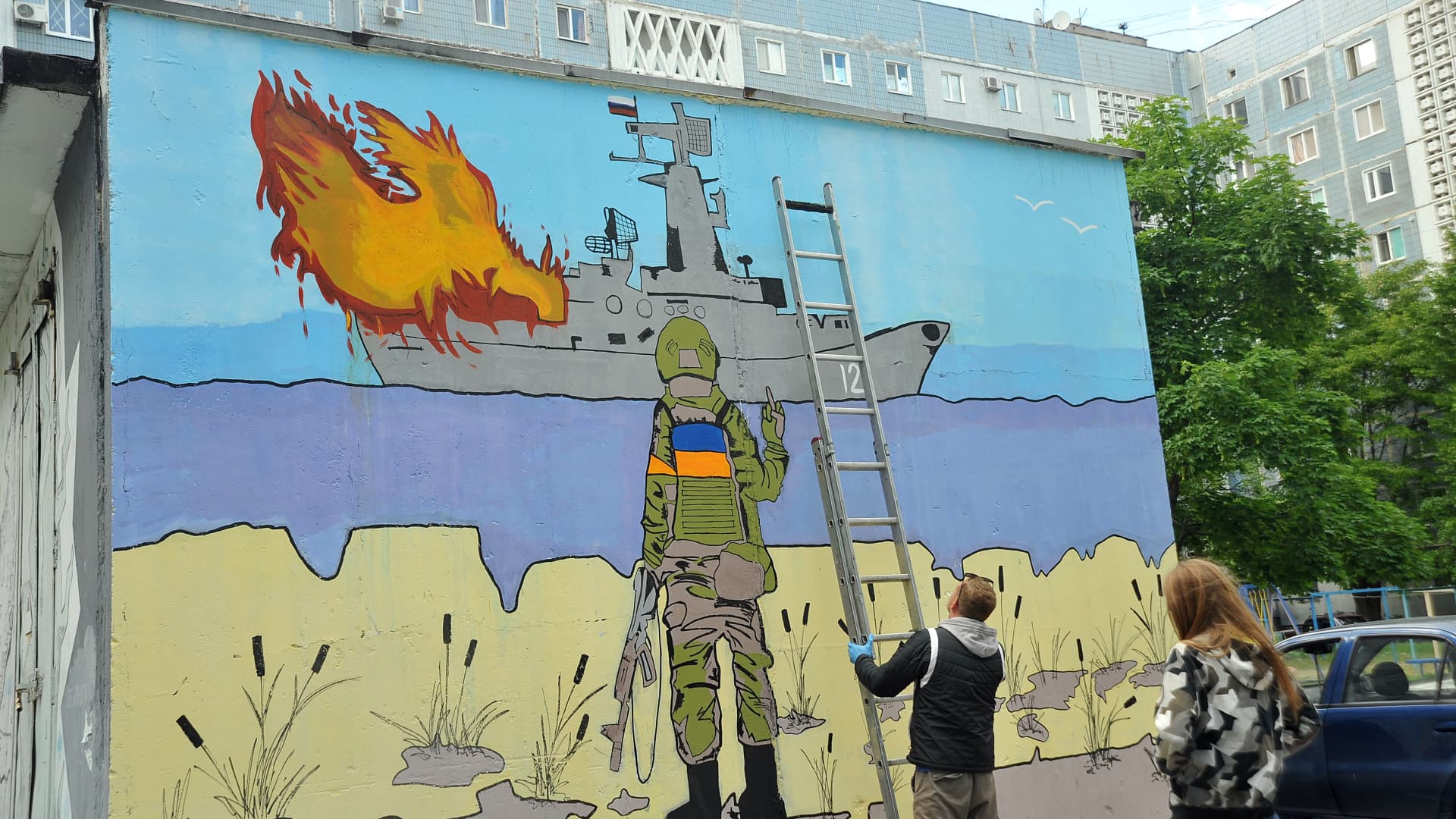 Street artist Denys Antiukov and his assistant Hanna work on a mural inspired by the Russian Warship, Go F... Yourself! postage stamp in the Khortytskyi district of Zaporizhzhia, southeastern Ukraine.