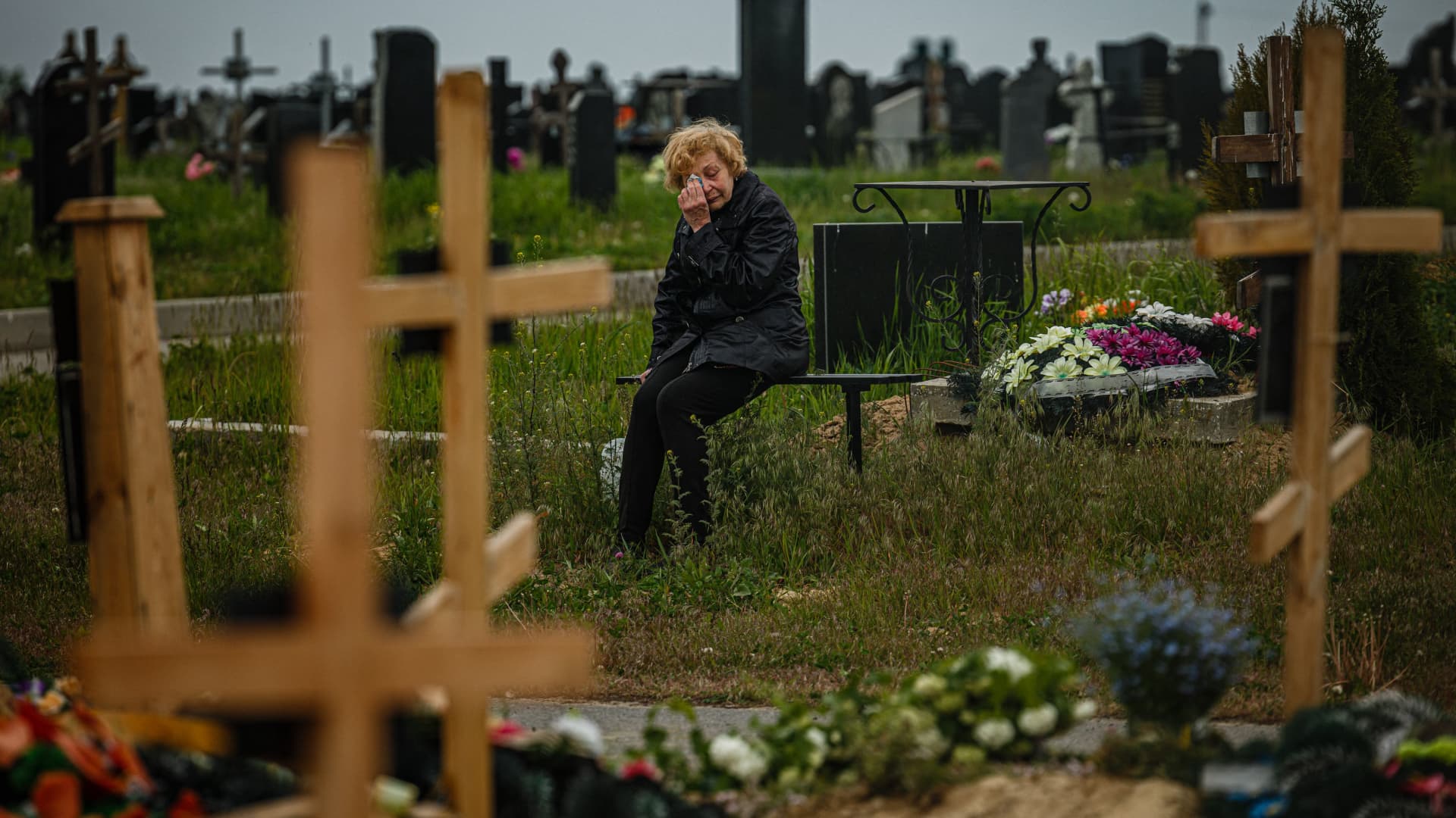 A woman mourns while visiting the grave of Stanislav Hvostov, 22, a Ukrainian serviceman killed during the Russian invasion of Ukraine, in the military section of the Kharkiv cemetery number 18 in Bezlioudivka, eastern Ukraine on May 21, 2022.