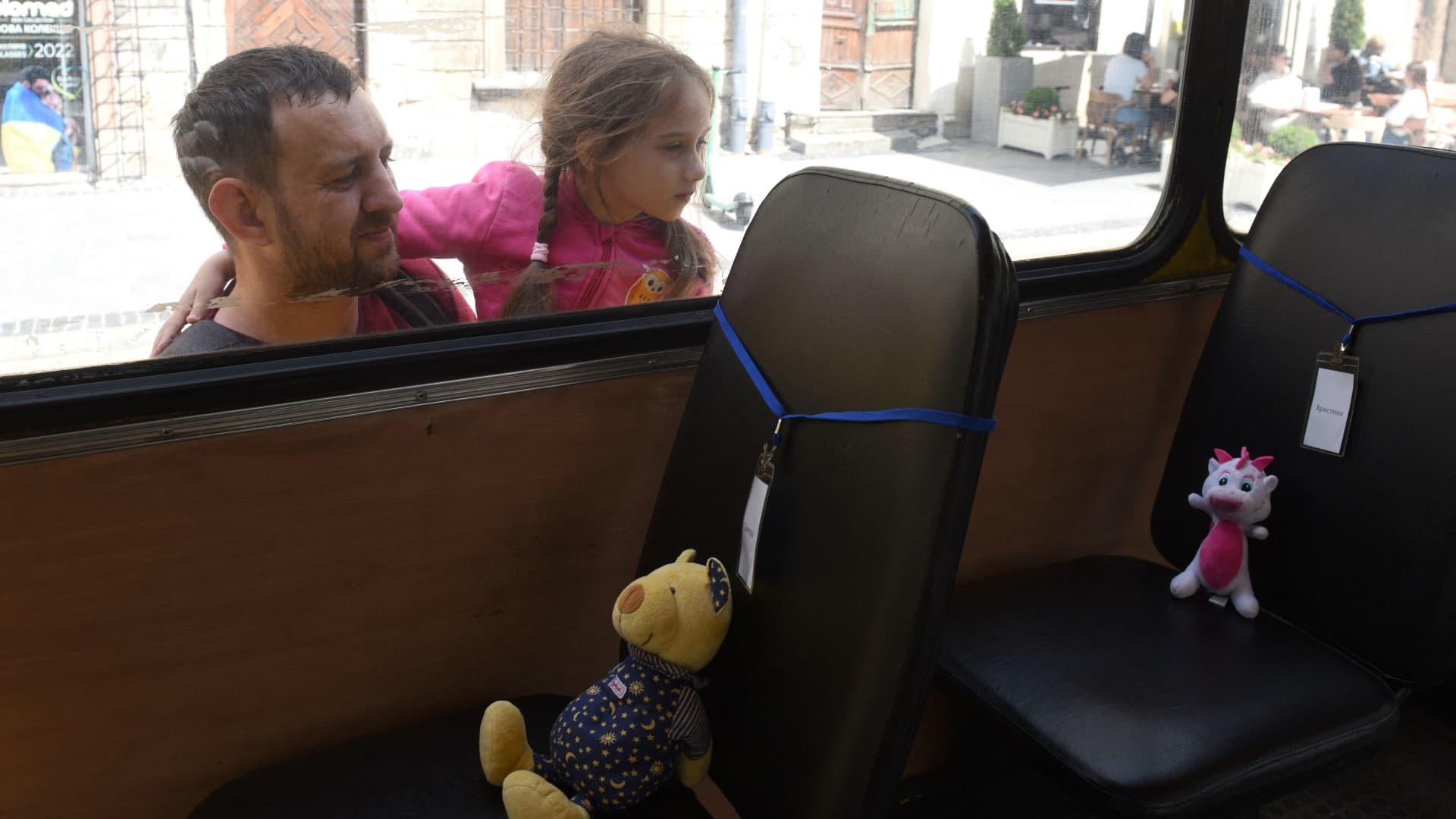A girl looks into an empty school bus where stuffed toys symbolizing each of 243 killed Ukrainian children are displayed on seats during an action marking the International Children's Day, in Lviv on June 1, 2022, amid the Russian invasion of Ukraine. 