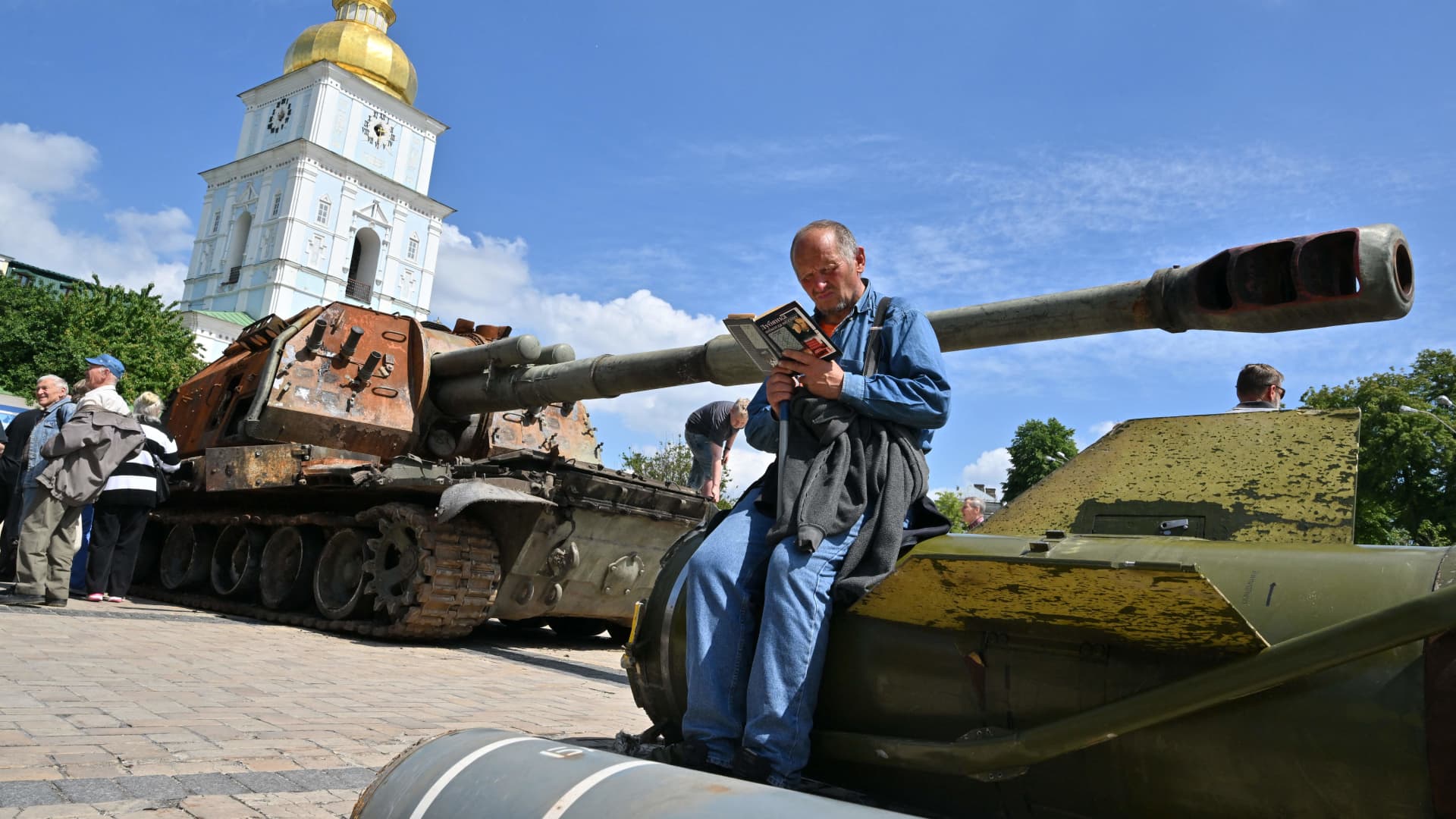 An elderly man reads a book as sits on a fragment of Russian rocket Tochka-U at open air exposition of destroyed Russian equipment in the center of Kyiv on June 1, 2022 amid the Russian invasion of Ukraine.