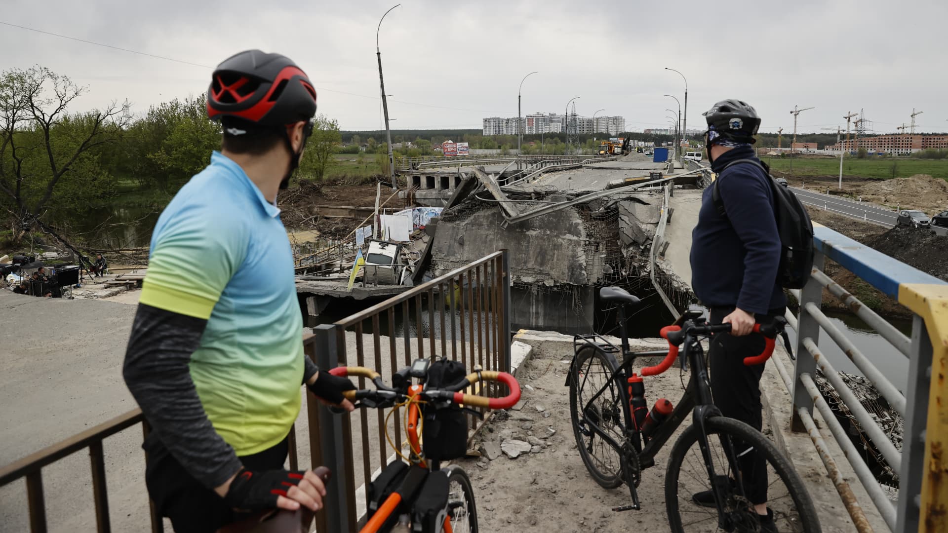 Cyclists view a collapsed bridge ahead of the World Bicycle Day in Irpin in Ukraine's Kyiv Oblast on May 07, 2022 as the Russia-Ukraine war continues. 