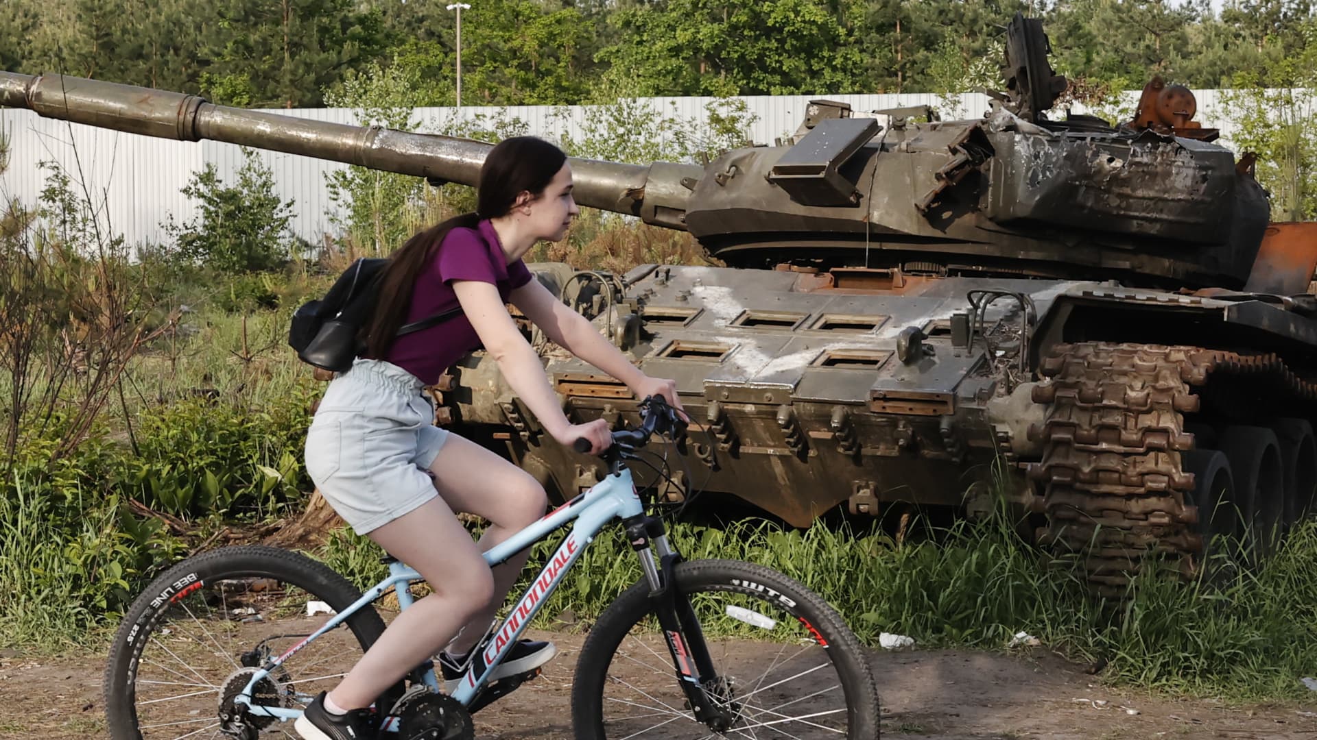 A cyclist rides in front of a wrecked tank ahead of the World Bicycle Day in village of Dmitrivka in Ukraine's Kyiv Oblast on June 01, 2022 as the Russia-Ukraine war continues. 