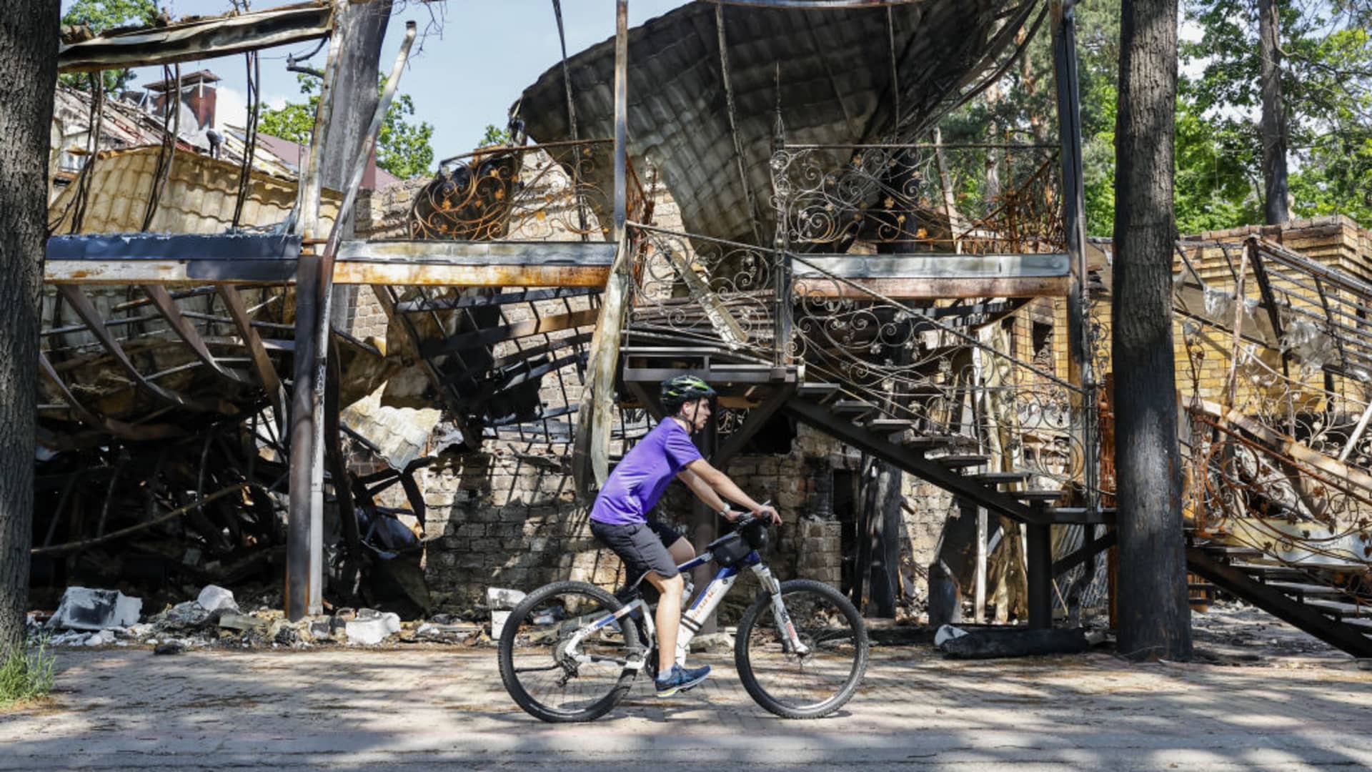 A cyclist rides in front of a collapsed house ahead of the World Bicycle Day in Ukraine's Kyiv Oblast on June 01, 2022 as the Russia-Ukraine war continues.