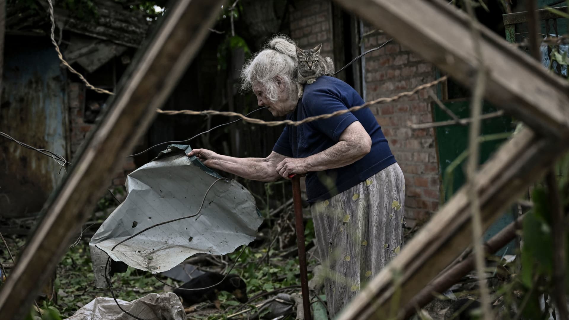 An eldery woman, with a cat on her shoulder, tries to clean her yard from debris after a missile strike killing one old woman in the city of Droujkivka at the eastern Ukrainian region of Donbas on June 5, 2022.