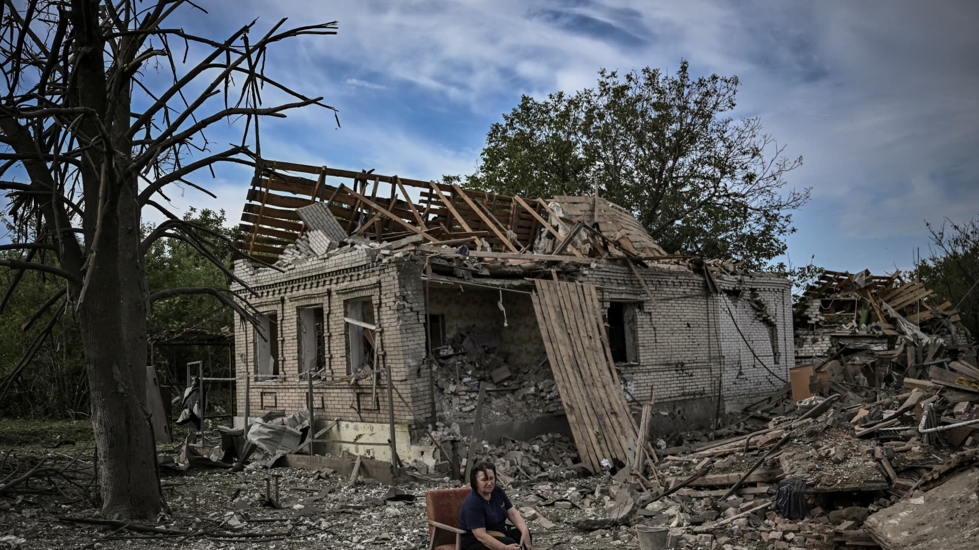 A woman sits on a chair in front of a destroyed house after a missile strike, which killed an old woman, in the city of Druzhkivka (also written Druzhkovka) in the eastern Ukrainian region of Donbas on June 5, 2022.