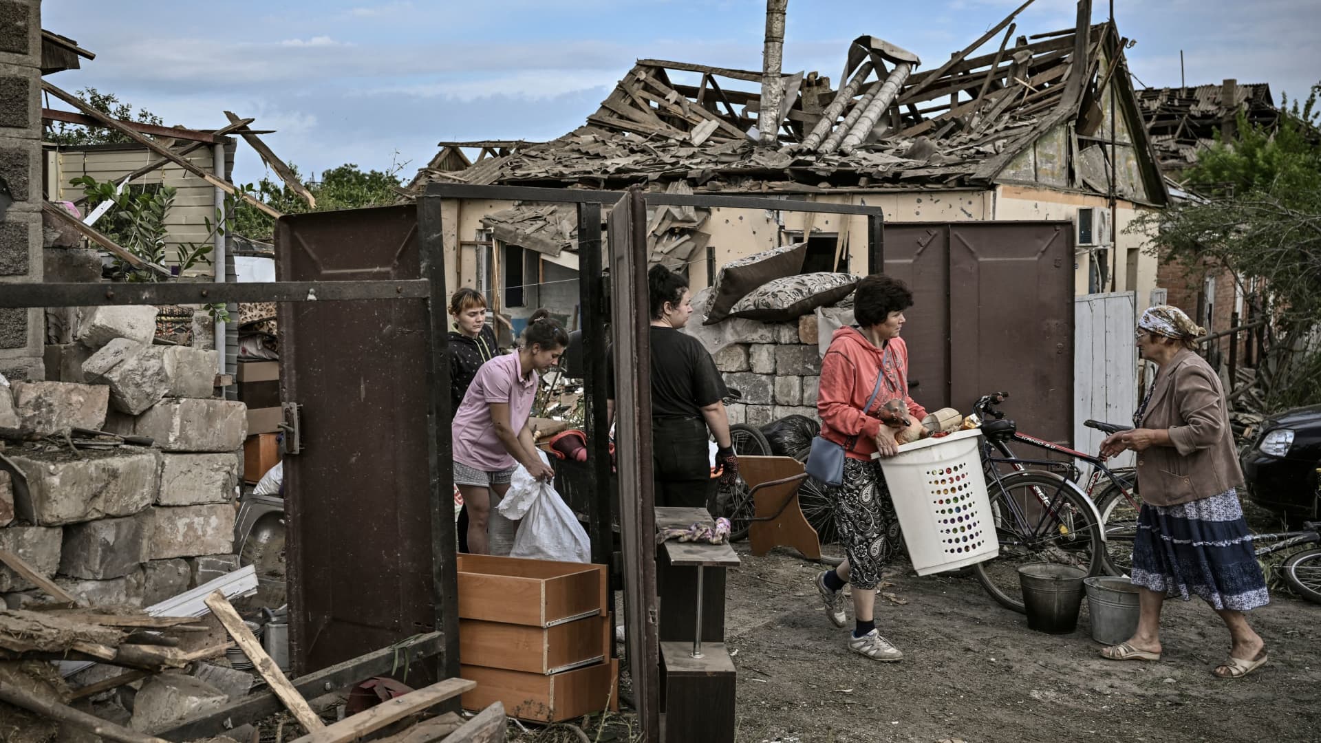 People collect personal belongings from their destroyed house after a missile strike, which killed an old woman, in the city of Druzhkivka (also written Druzhkovka) in the eastern Ukrainian region of Donbas on June 5, 2022.