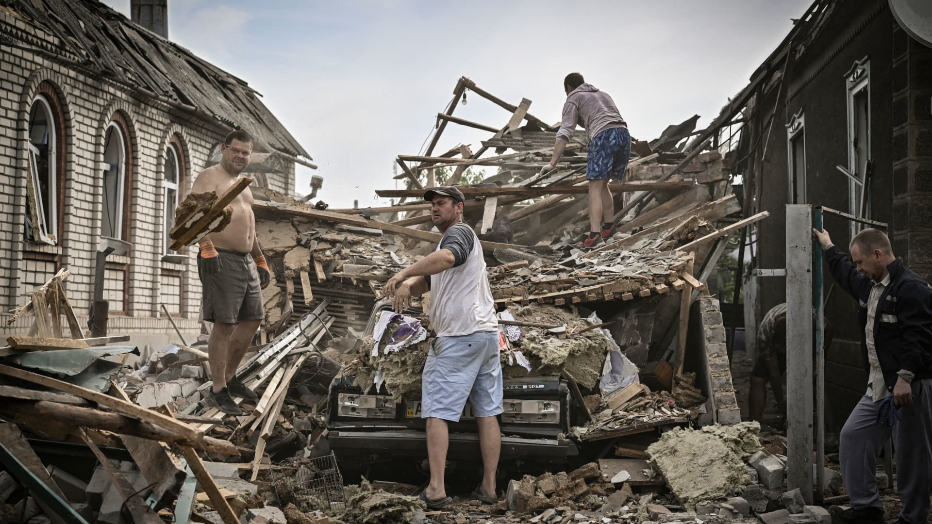 People clean the debris from their destroyed house after a missile strike, which killed an old woman, in the city of Druzhkivka (also written Druzhkovka) in the eastern Ukrainian region of Donbas on June 5, 2022.