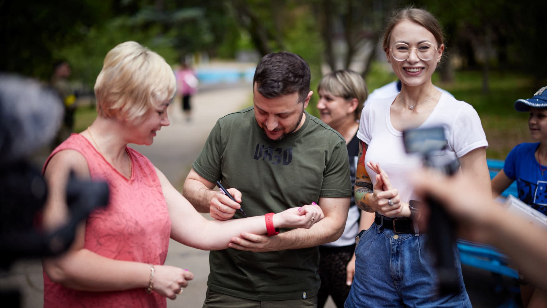 Ukraine's President Volodymyr Zelenskyy lefts a sign on an arm of his supporter as he attends a meeting with internally displaced people from Mariupol, amid Russia's attack on Ukraine continues, in Zaporizhzhia region, Ukraine June 5, 2022.