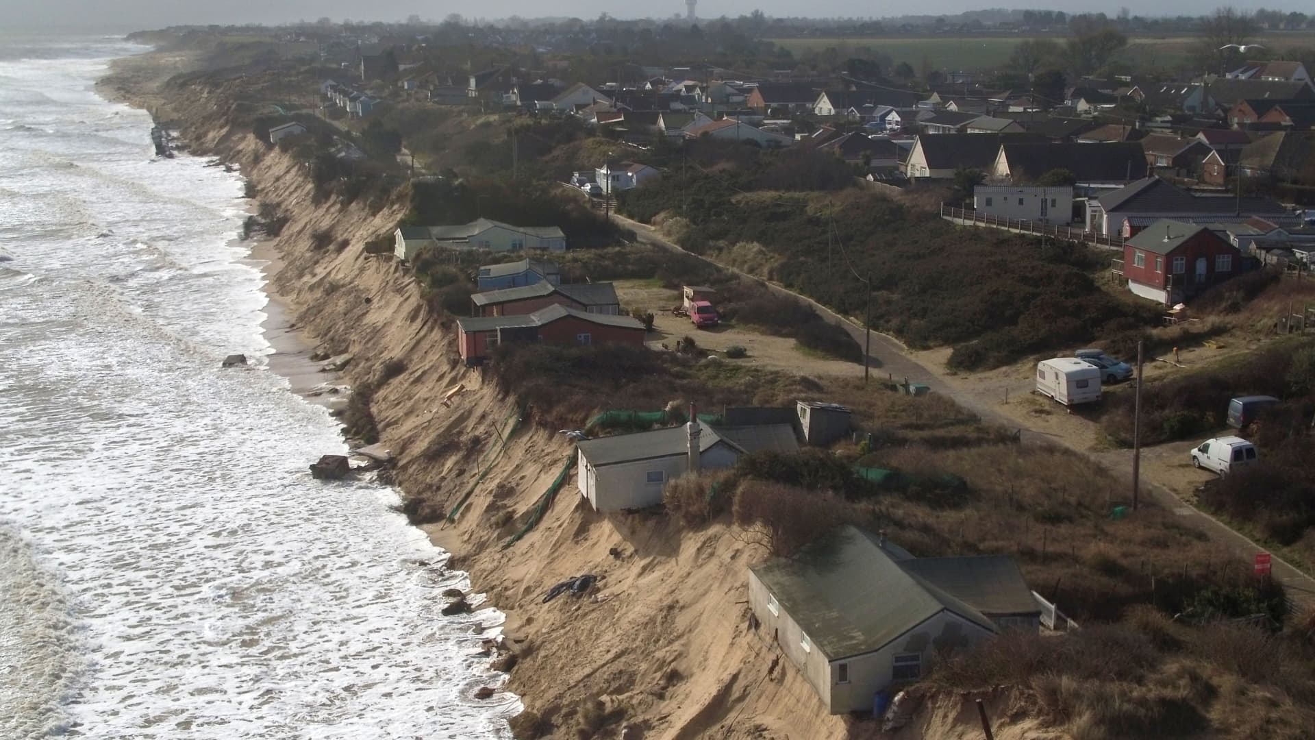 This image from 2018 shows properties on the edge of a cliff on the coast of Norfolk, England. Rising sea levels and coastal erosion pose a threat to many coastal communities around the world.