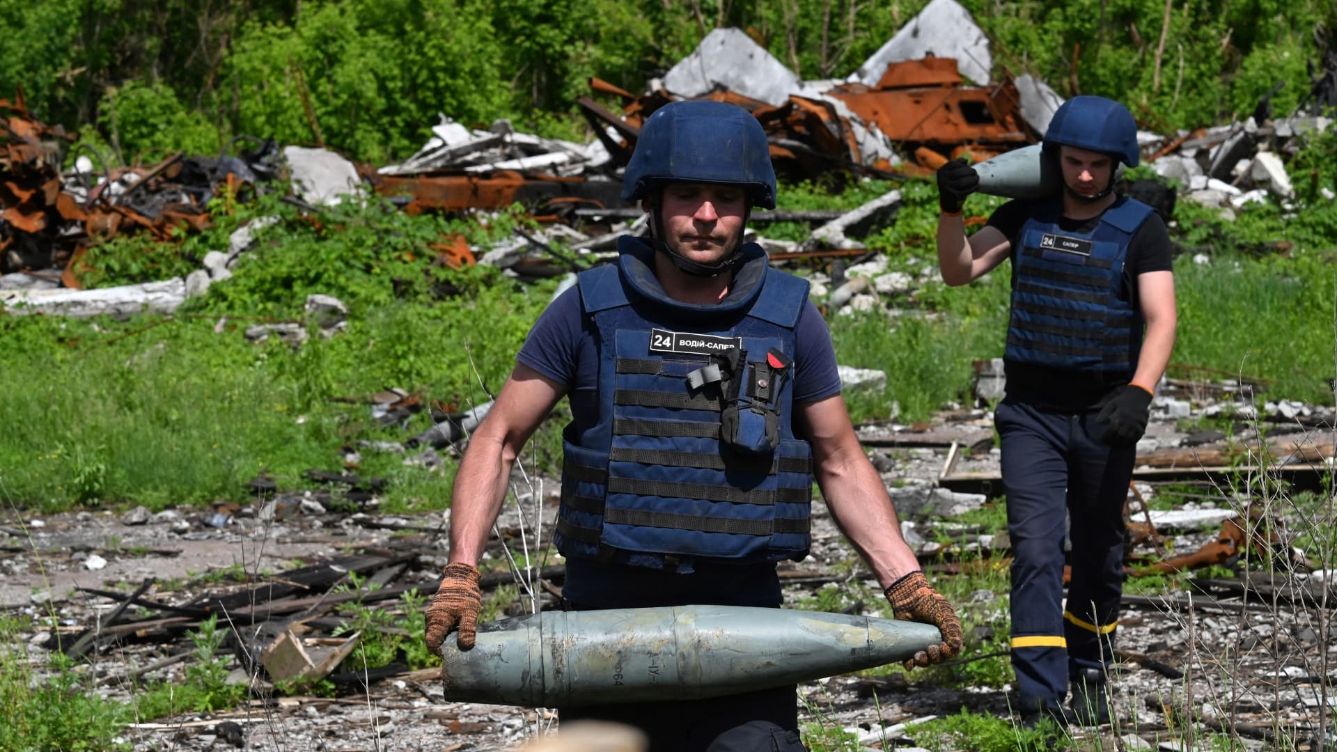 Ukrainian bomb disposal workers carry unexploded ordnance during mine clearance work in the village of Yahidne, in the liberated territories of the Chernihiv region on June 7, 2022 amid the Russian invasion of Ukraine.