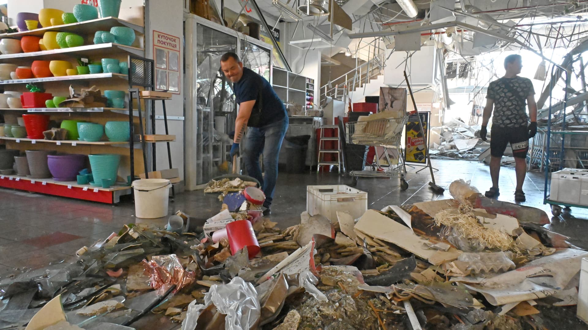 Employees of a supermarket, partially destroyed by a missile attack on the southeastern outskirts of the Ukrainian city of Kharkiv clean up the rubble of the building in the trading hall on June 8, 2022, amid the Russian invasion of Ukraine.