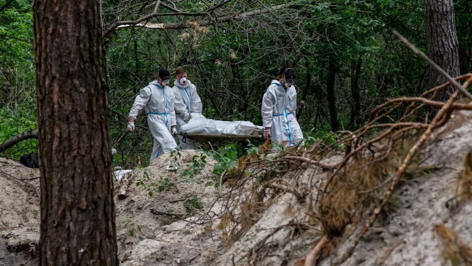 An excavation team carries a body of Ukrainian civilian murdered by Russian army in a forest near Bucha, Ukraine - June 13, 2022. The bodies were discovered by a patrol of Territorial Defence Forces and were located near tranches built by the Russian army when it occupied the territory. Seven bodies were excavated from a mass grave. Some of the bodies have signs of being tied and  shot at. An investigation will follow. (Photo by Dominika Zarzycka/NurPhoto via Getty Images)
