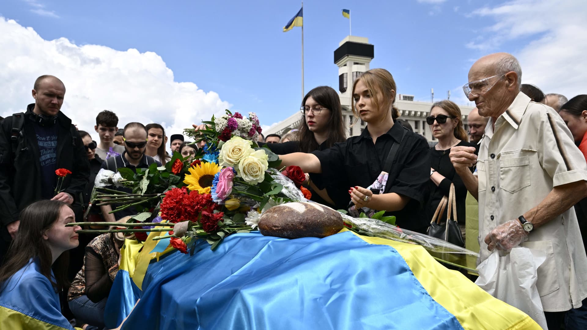 TOPSHOT - Mourners pay their respects next to the coffin of killed Ukrainian serviceman Roman Ratushny during a farewell ceremony in Kyiv on June 18, 2022, amid the Russian invasion of Ukraine. - Roman Ratushny was a leading figure of Ukraine's pro-European Maidan movement, an anti-corruption activist, and fought Russian forces with the Ukrainian army. Roman Ratushny died on June 9 near Izium, in the Kharkiv region, where Ukrainian forces are confronting the Russian army.at the age of 24. (Photo by Genya SAVILOV / AFP) (Photo by GENYA SAVILOV/AFP via Getty Images)