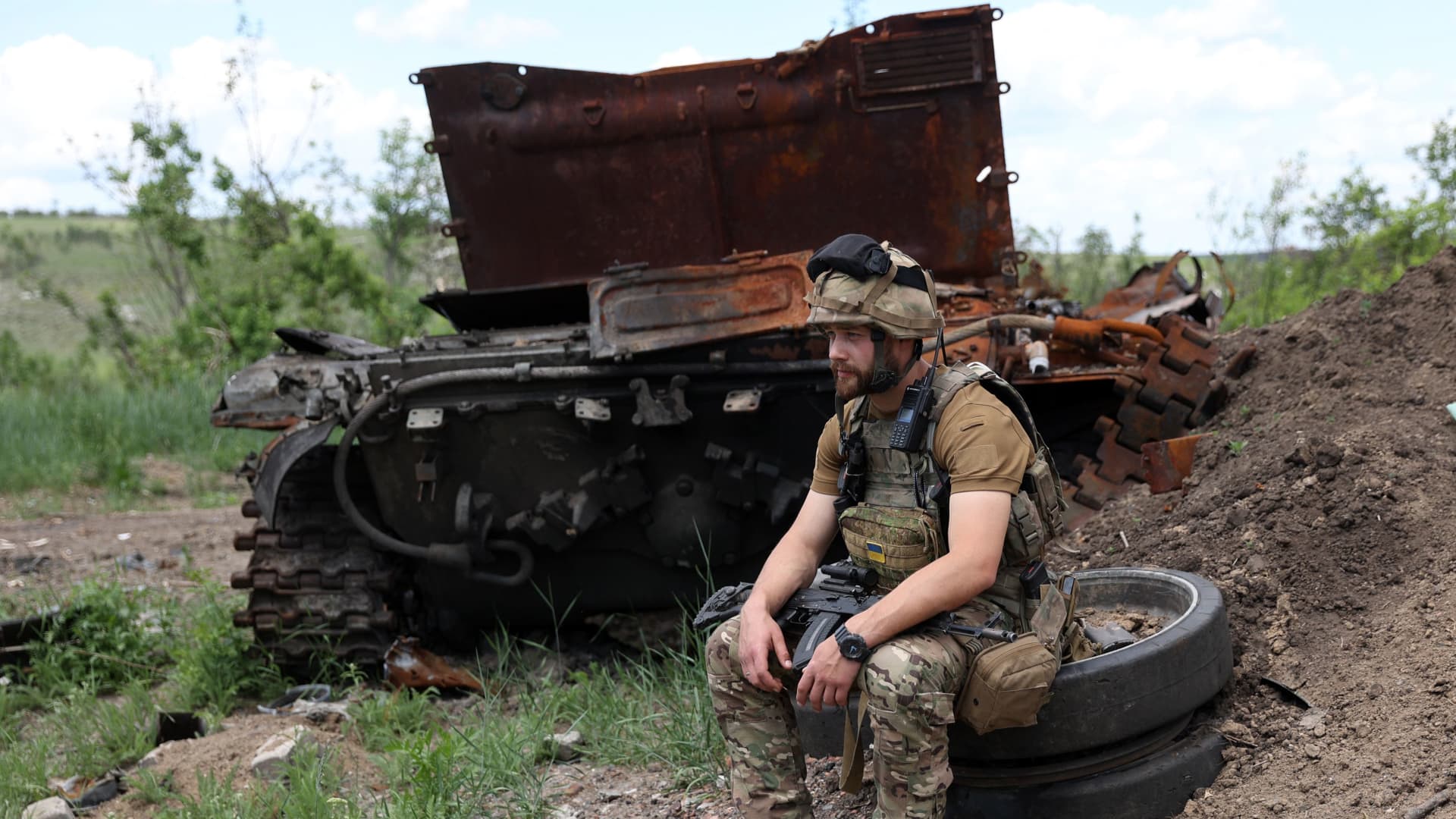 A Ukrainian serviceman sits next to a destroyed Russian tank at an abandoned Russian position near the village of Bilogorivka not far from Lysychansk, Luhansk, on June 17, 2022.