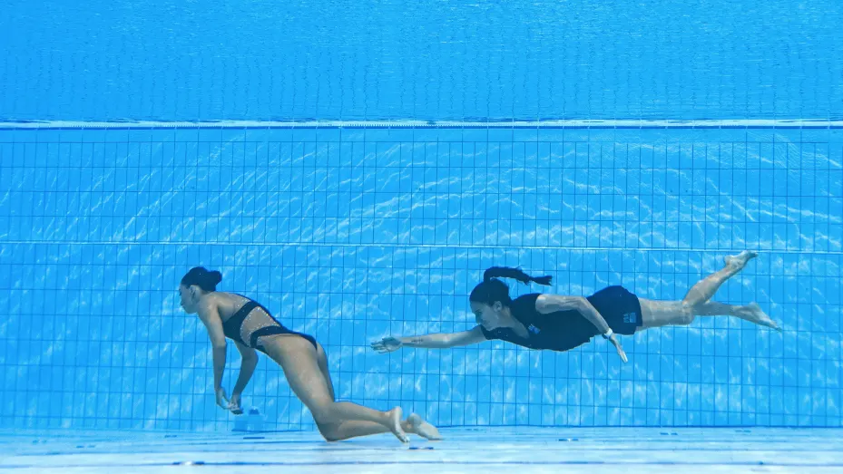 A member of Team USA (R) swims to recover USA's Anita Alvarez (L), from the bottom of the pool.