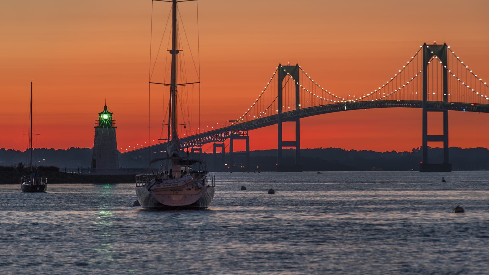 Goat Island lighthouse and the Jamestown or Pell Bridge at sunset.