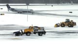 Snow is cleared on a runway as a plane taxis into Manchester-Boston Regional Airport in Manchester, N.H.