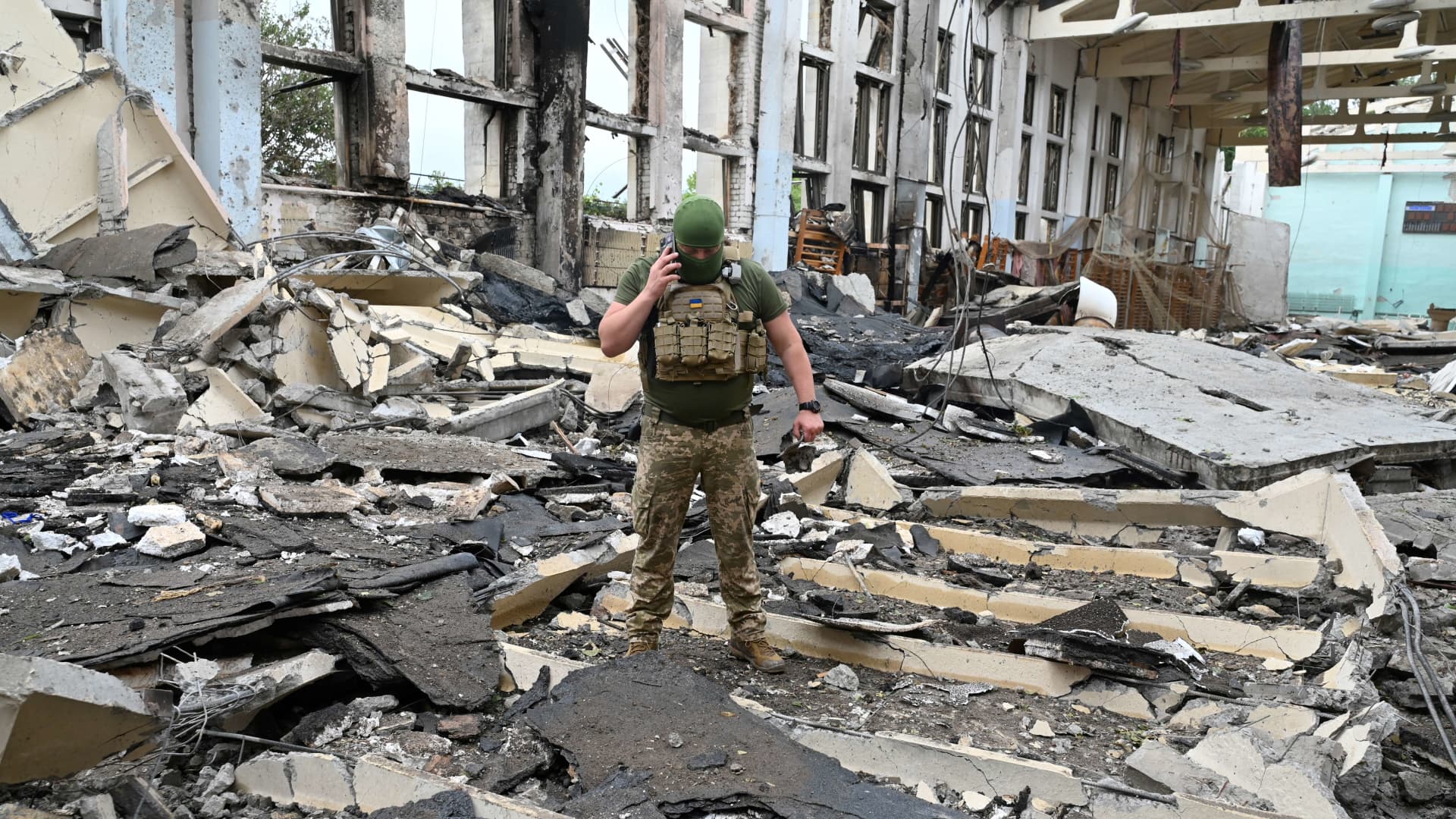 A Ukrainian serviceman talks by phone as he walks through the rubbles of a building of the Polytechnic Sports Complex of the Kharkiv National Technical University after it was hit by Russian missile in Kharkiv on June 24, 2022, amid Russian invasion of Ukraine. 