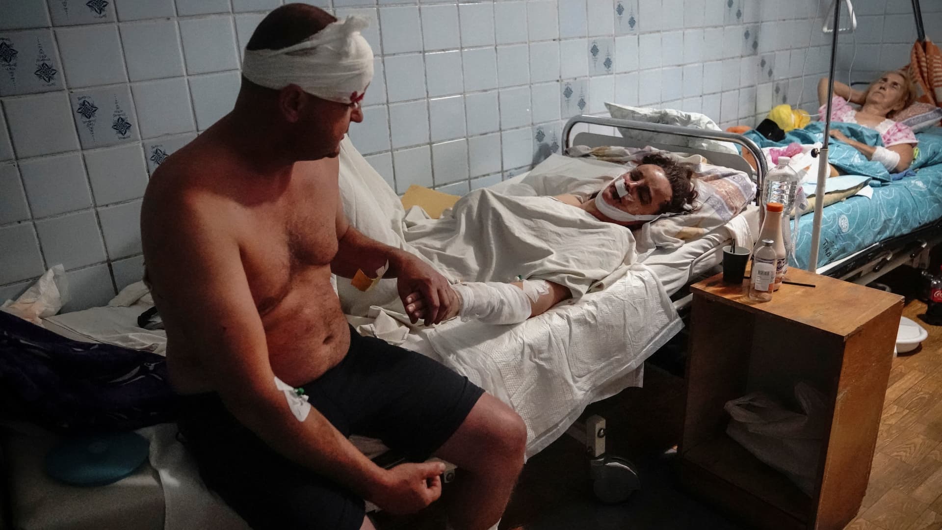 A couple wounded in a shopping mall hit by a Russian missile strike hold hands in a hospital as Russia's attack on Ukraine continues, in Kremenchuk, in Poltava region, Ukraine June 27, 2022.