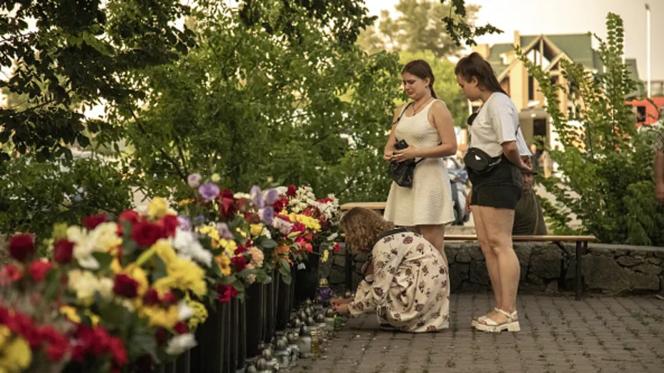 Las mujeres jóvenes lloran frente a un monumento hecho de flores a las víctimas civiles cerca de un centro comercial atacado por un misil en Kremenchuk, Ucrania, el 28 de junio de 2022.