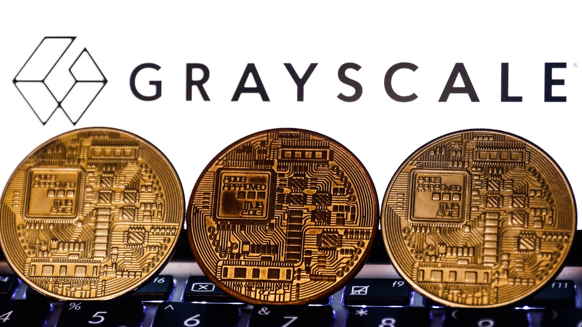 Representation of cryptocurrency and Gayscale logo displayed on a phone screen.