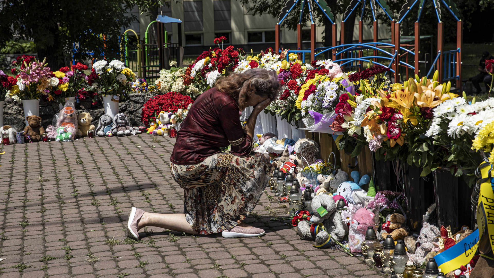 A woman mourns in front of a memorial made of flowers offered to the civilian victims nearby a shopping mall targeted by a missile strike in Kremenchuk, Ukraine, June 30th, 2022.