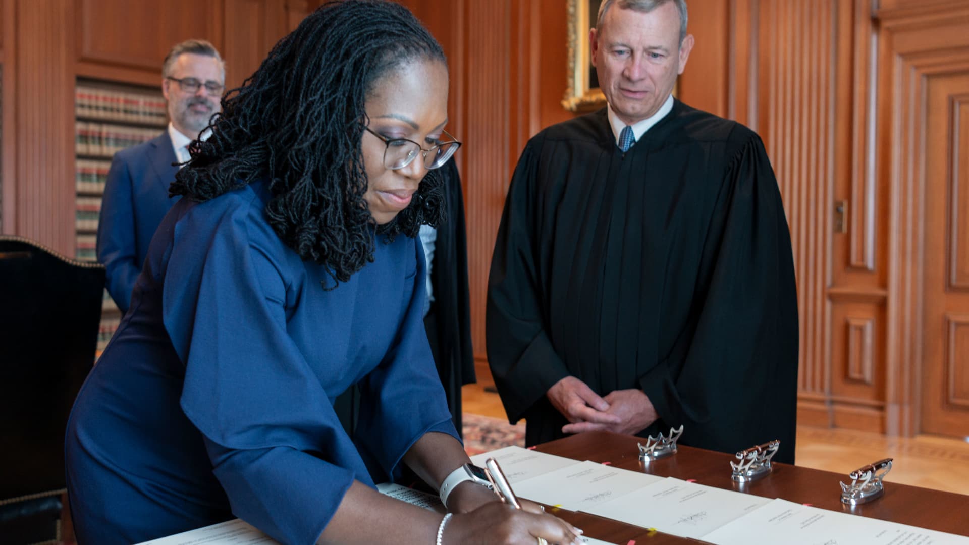 Chief Justice John G. Roberts, Jr., looks on as Justice Ketanji Brown Jackson signs the Oaths of Office in the Justices' Conference Room, Supreme Court Building.