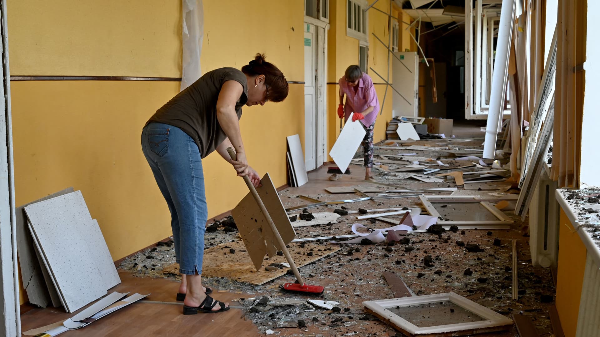 Teachers and employees clear debris in a corridor of a special comprehensive boarding school for visually impaired children which has suffered damages after a strike on its premises, in Kharkiv, on July 7, 2022, amid Russia's military invasion launched on Ukraine.