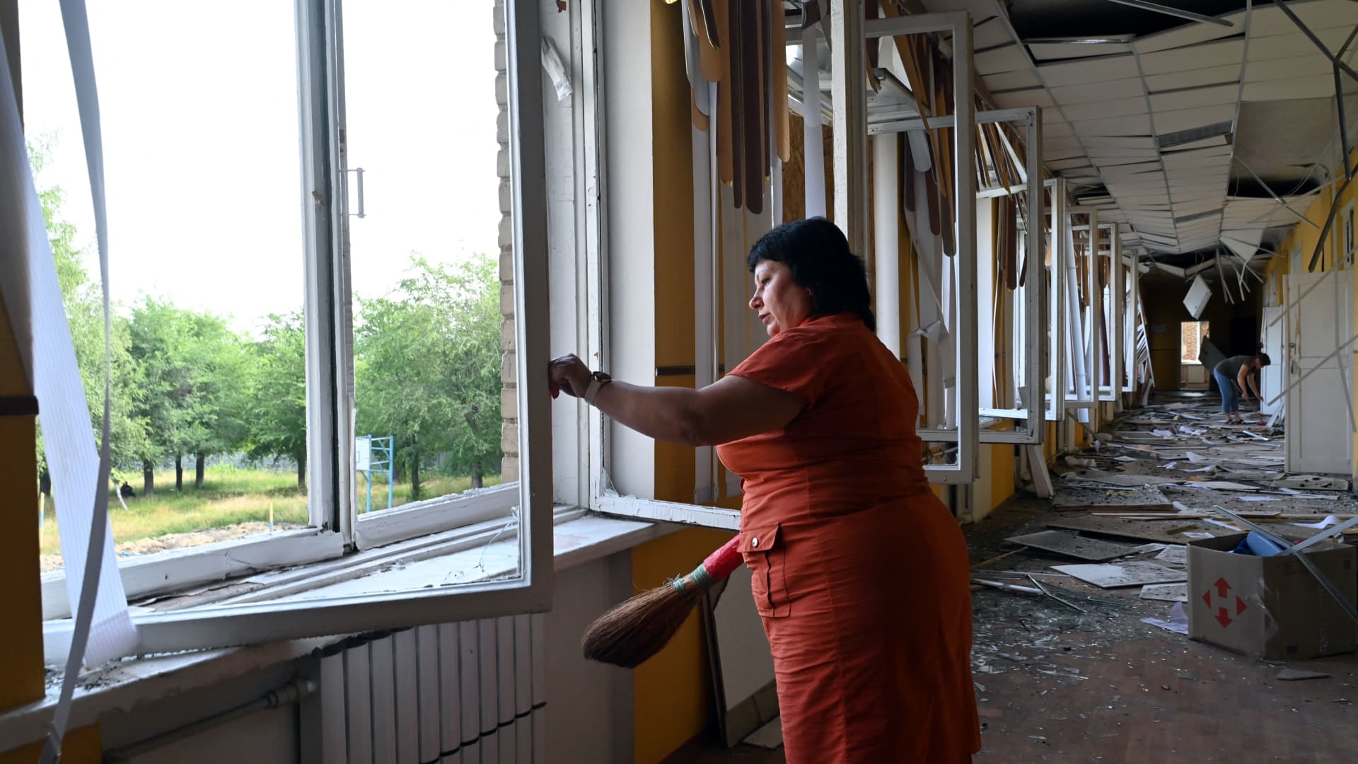 Teachers and employees clear debris in a corridor of a special comprehensive boarding school for visually impaired children which has suffered damages after a strike on its premises, in Kharkiv, on July 7, 2022, amid Russia's military invasion launched on Ukraine. 
