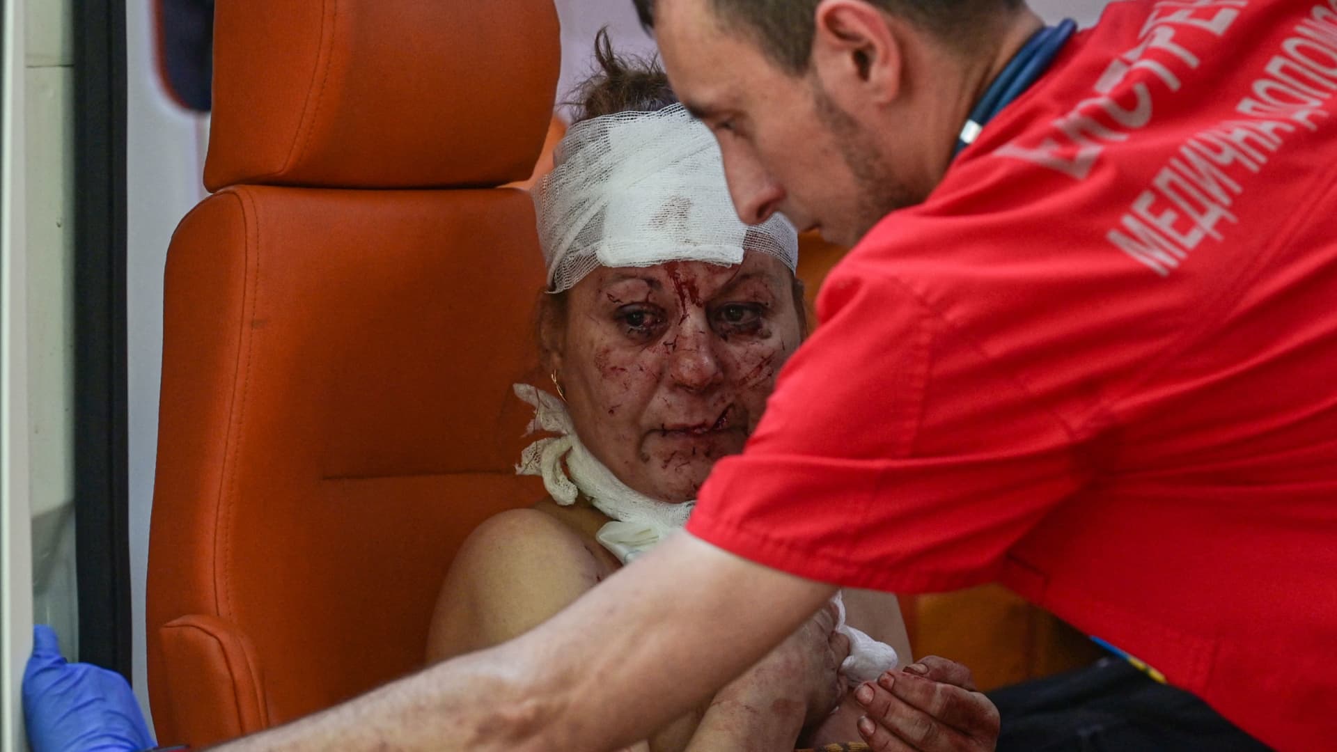 An injured woman is helped by an ambulance nurse after an air strike in the courtyard of hotel Industria and civilian residences in the center of Kramatorsk, on July 7, 2022.